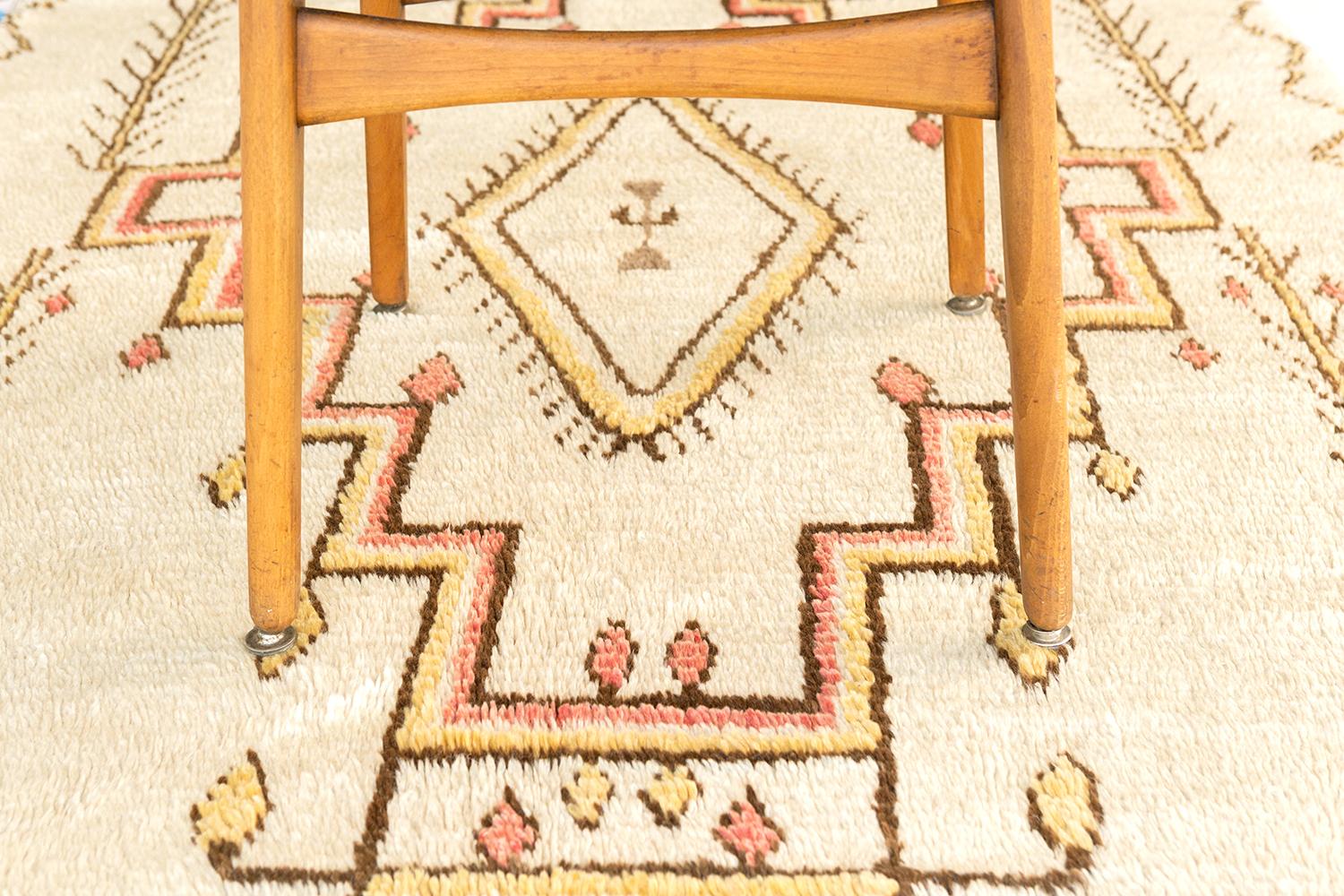 Emanating grace and sophistication, this Vintage Moroccan Azilal Tribe rug features a symbolic pattern in the subtle tones of french rose, cream, tan and ivory. The tribal design composed of varying lozenges with solid and jagged edges, fishbones