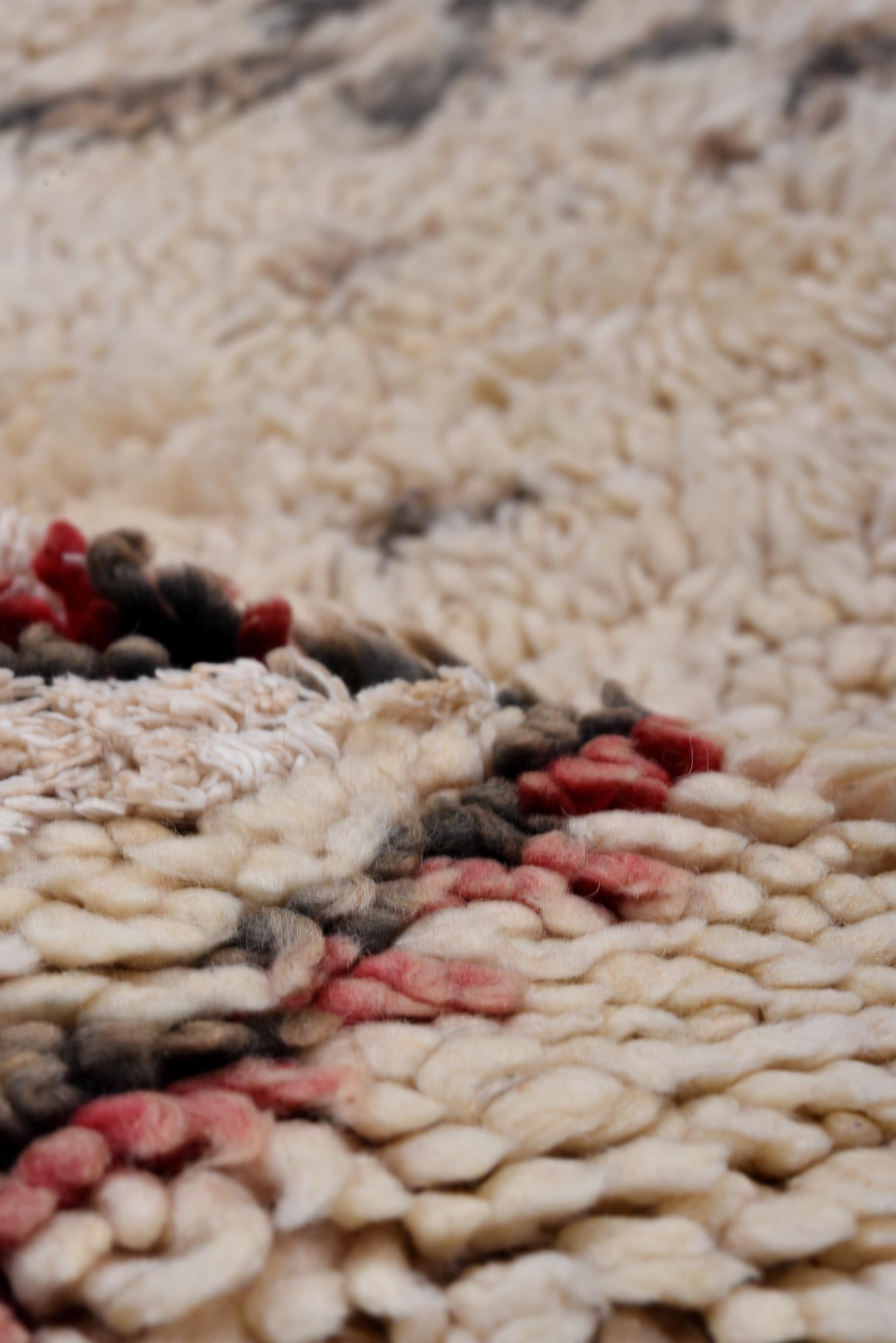 This vintage Moroccan rug showcases a classic Berber diamond lattice pattern, rendered in charcoal and accented with muted crimson tones on a warm ivory ground. The hand-knotted pile is plush and inviting, providing a tactile richness that reflects
