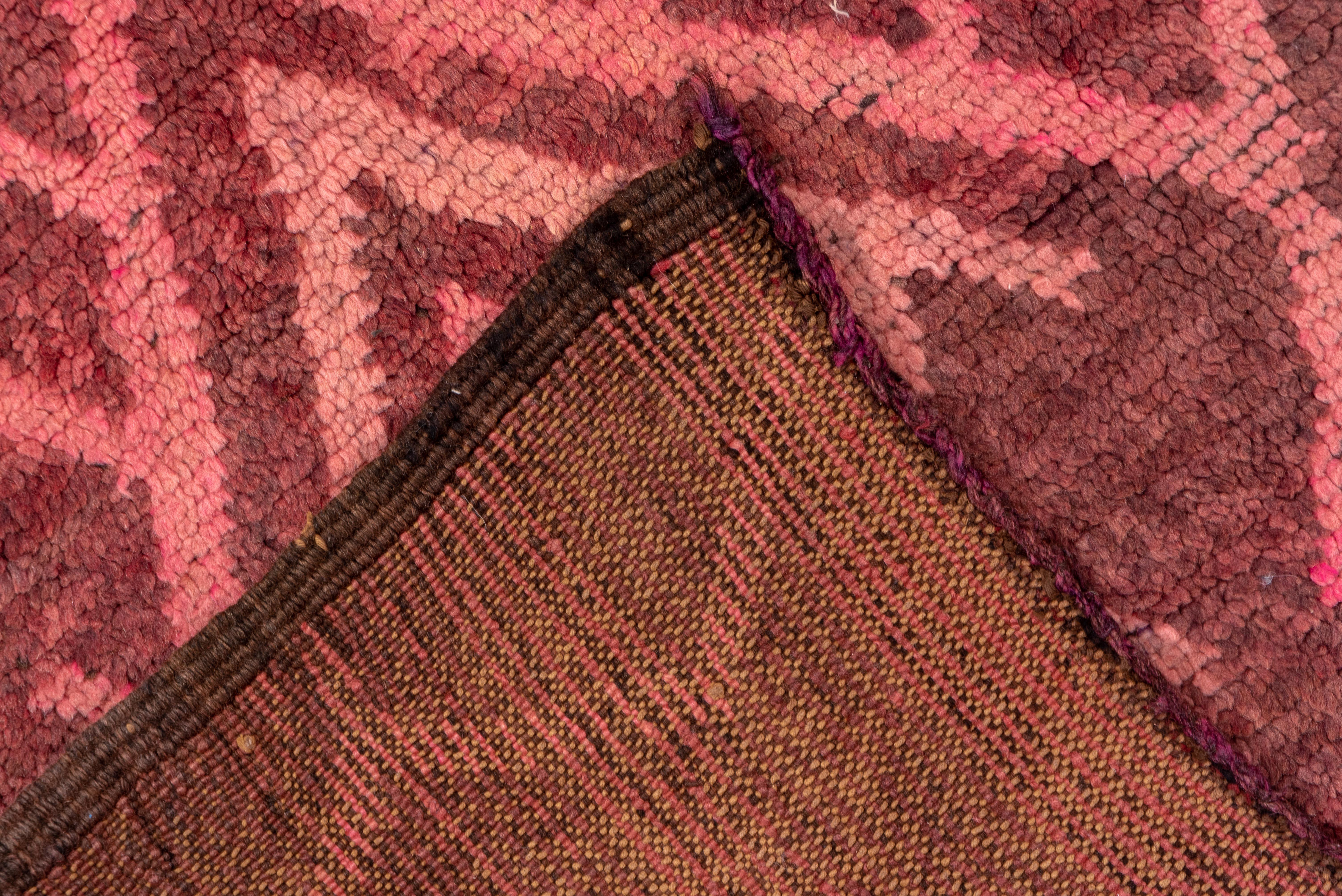 Ein raffinierter marokkanischer Läufer mit einer rhythmischen Reihe von Rautenmedaillons und gestuften Motiven in einer warmen Farbpalette aus Rosé, Terrakotta und sanftem Braun. Dieser Teppich besticht durch seine Farbtiefe und die subtilen