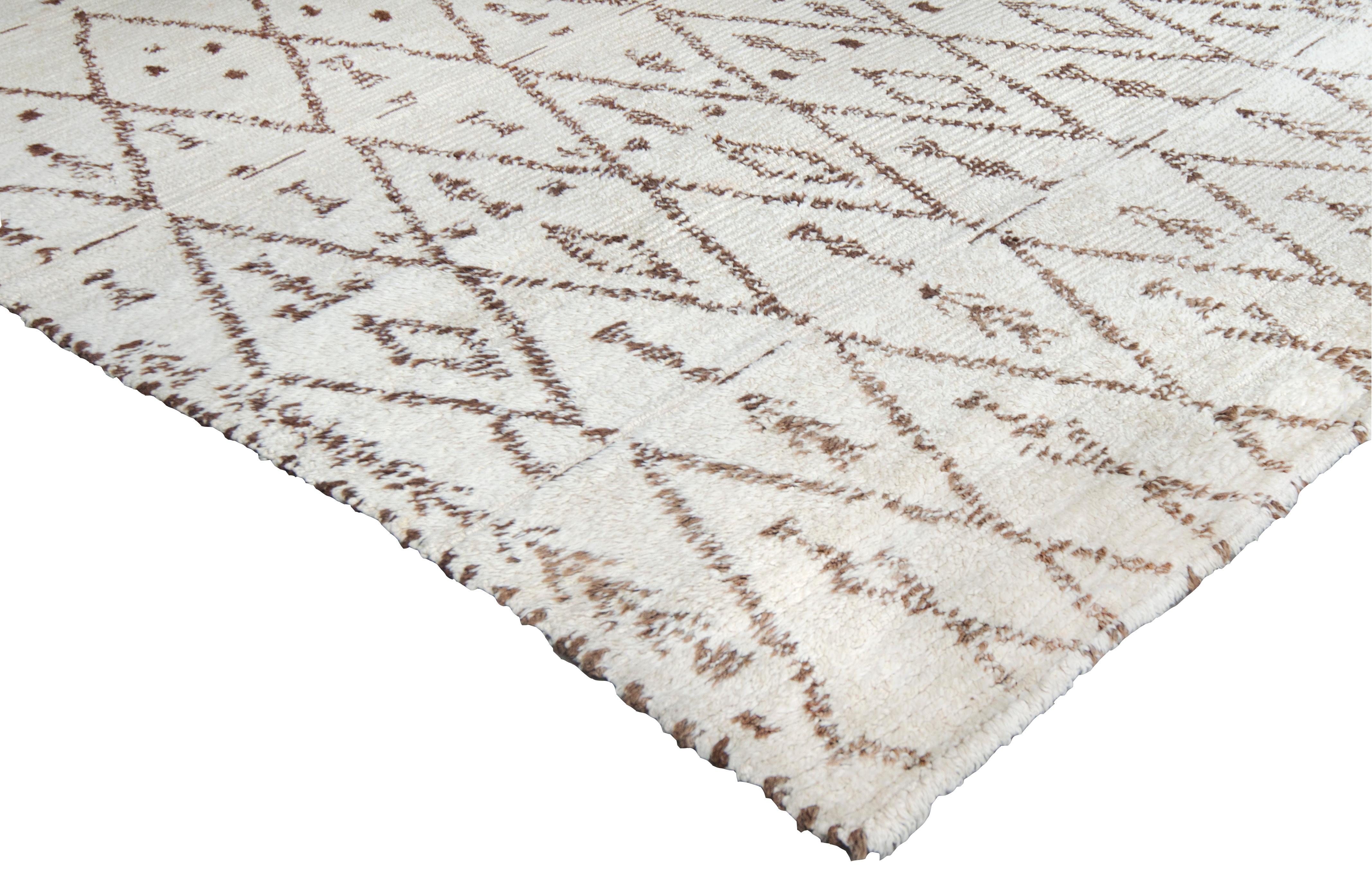 Von der Vintage-Deko inspirierter Teppich aus der Mitte des 20. Jahrhunderts, handgeknüpft in Marokko aus feinster Wolle. Das unverwechselbare Stammesmuster besteht aus verschiedenen Motiven, die in das dunkelbraune, geometrische Muster