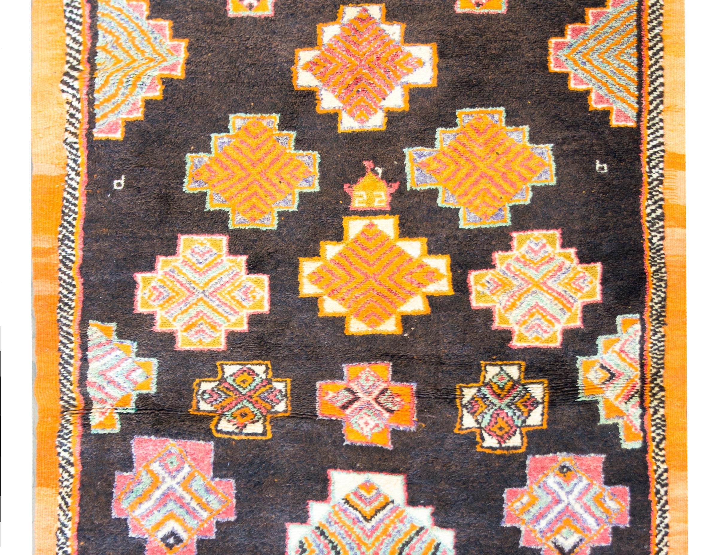 A bold and beautiful mid-20th century Moroccan rug with the best all-over diamond pattern woven in a kaleidoscope of colors including bright orange, pink, yellow, teal, and white, and all set against a black background. The border is simple with a