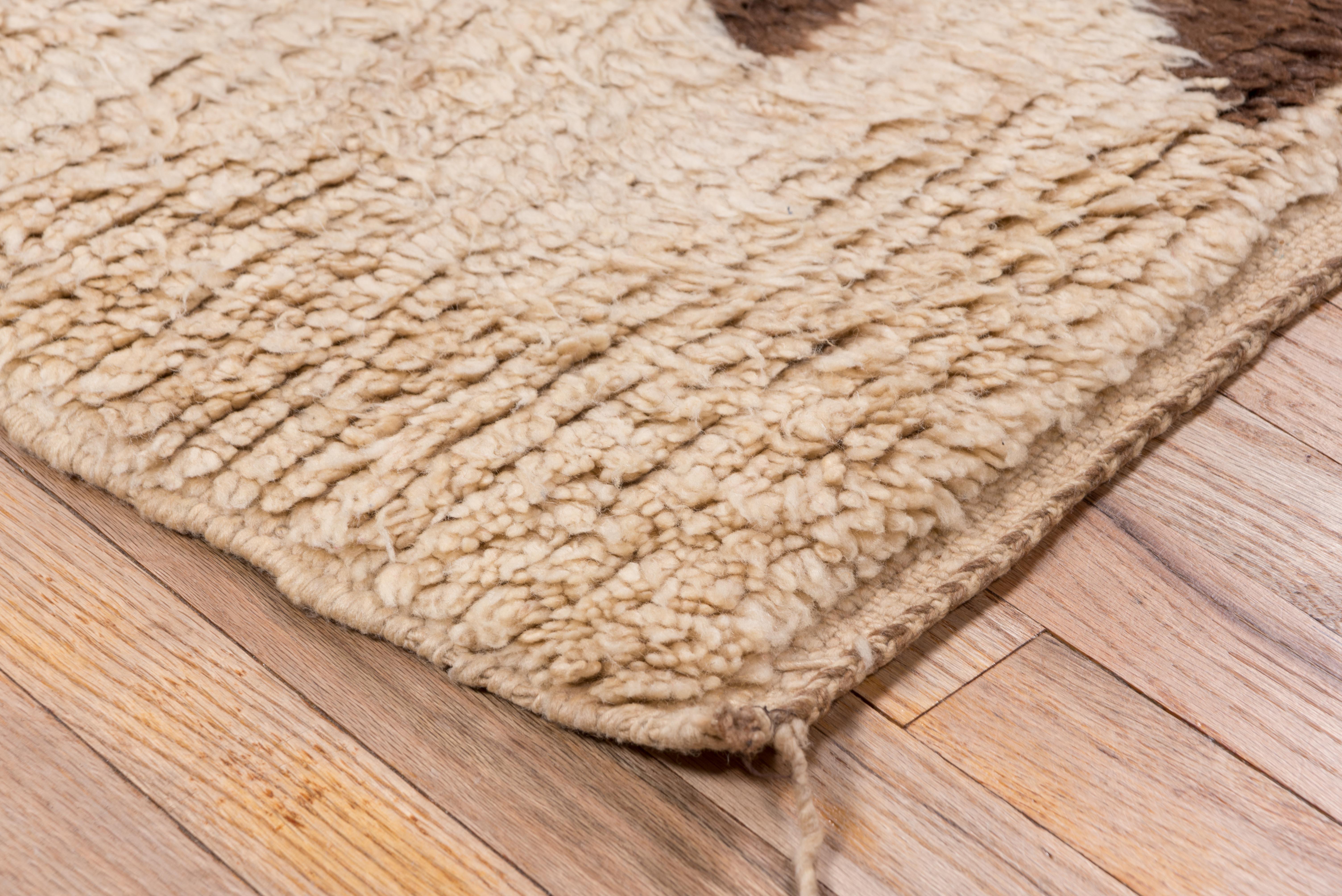 Esta alfombra marroquí vintage, en una paleta de crema cálido y marrón suave, destila carácter artesanal con sus motivos triangulares apilados dispuestos en una secuencia vertical totémica. Las fibras de lana natural le confieren un tacto denso y