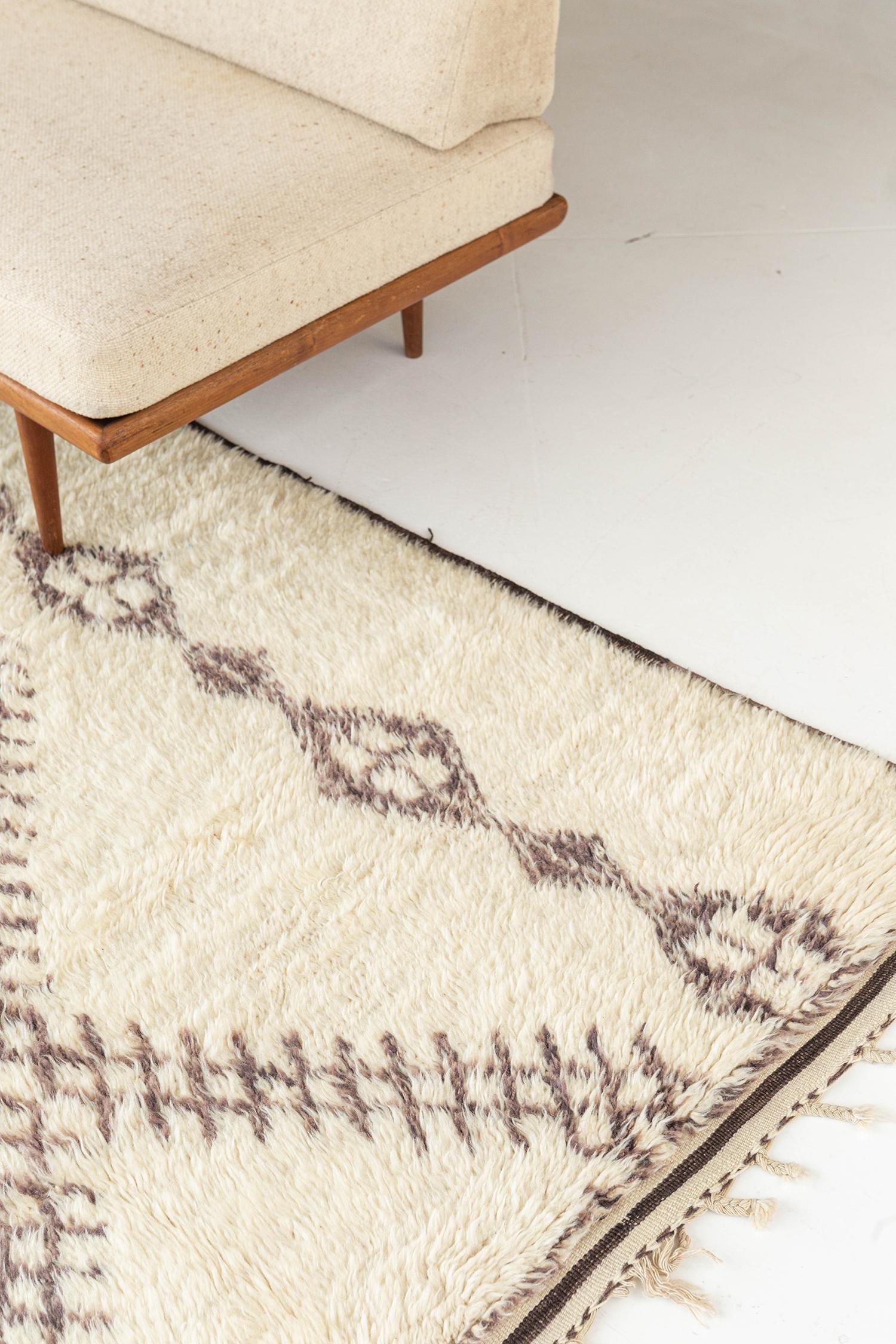 Accoccolati con questo tappeto marocchino in stile domestico della nostra collezione Atlas. Accogliente, caldo e confortevole, insieme a colori scuri e chiari. Le losanghe giocose con lati allungati e frange si abbinano agli interni della tua casa
