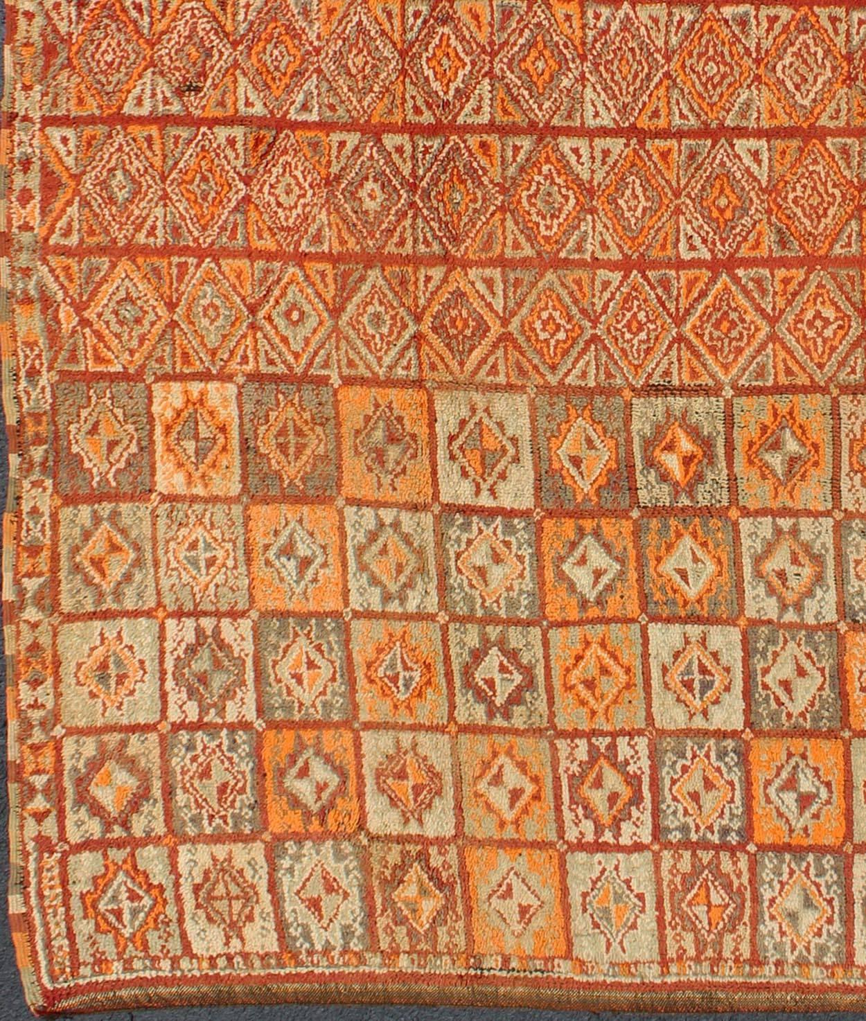 Marokkanischer Vintage-Teppich in Herbstfarben, Rot, Kürbis, Orange und Hellgrün
Dieser farbenfrohe marokkanische Teppich zeichnet sich durch ein Gitter aus geometrischen Mustern und eine Vielzahl von herbstlichen Farben wie Rot, Kürbis, Orange und
