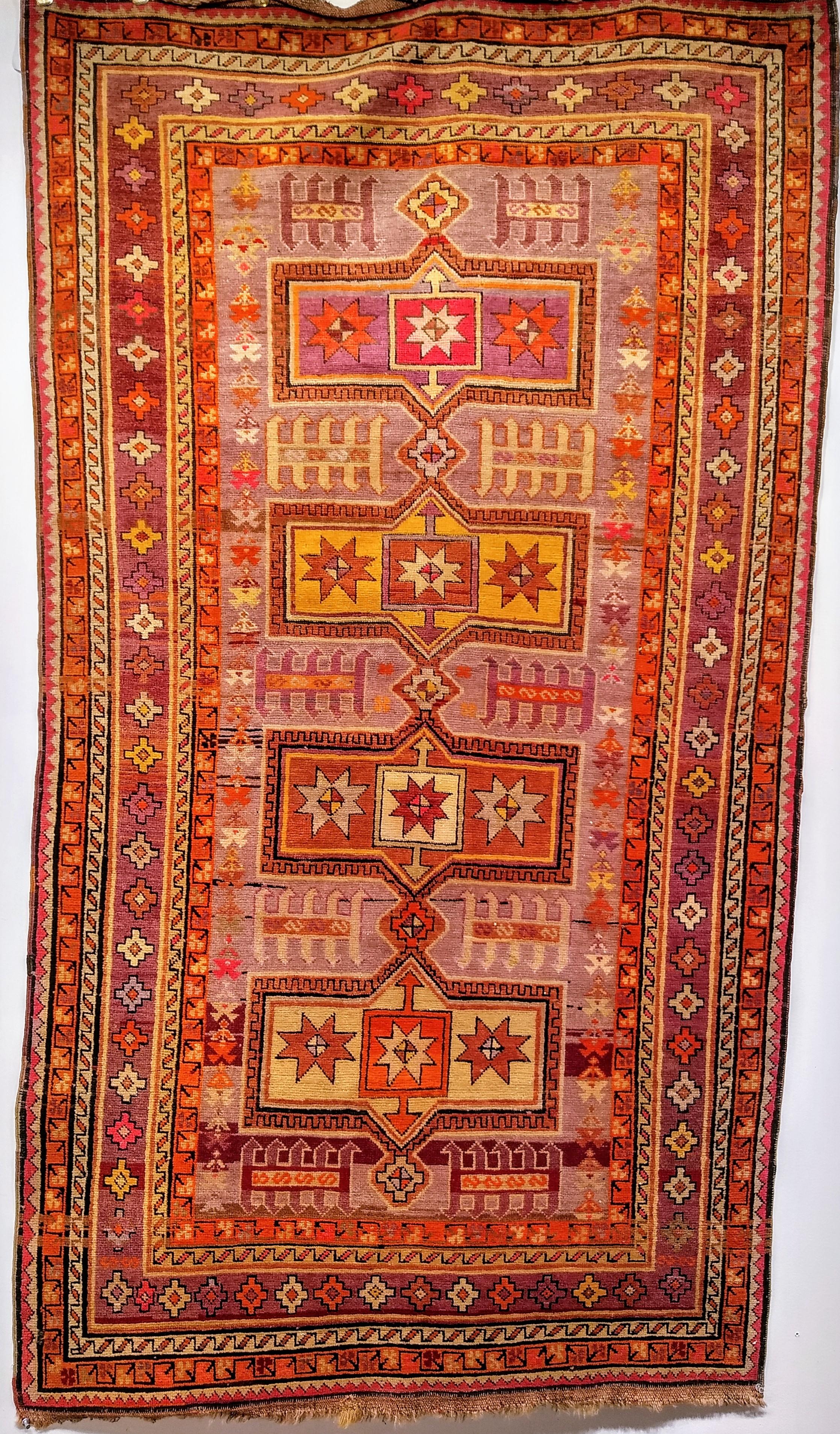 Vintage Moroccan rug in a geometric pattern in vibrant colors including purple, pink, yellow, magenta, and orange. The rug's design and the color palette is intended to make its presence felt and appreciated.  It reminds one of the wonderful and