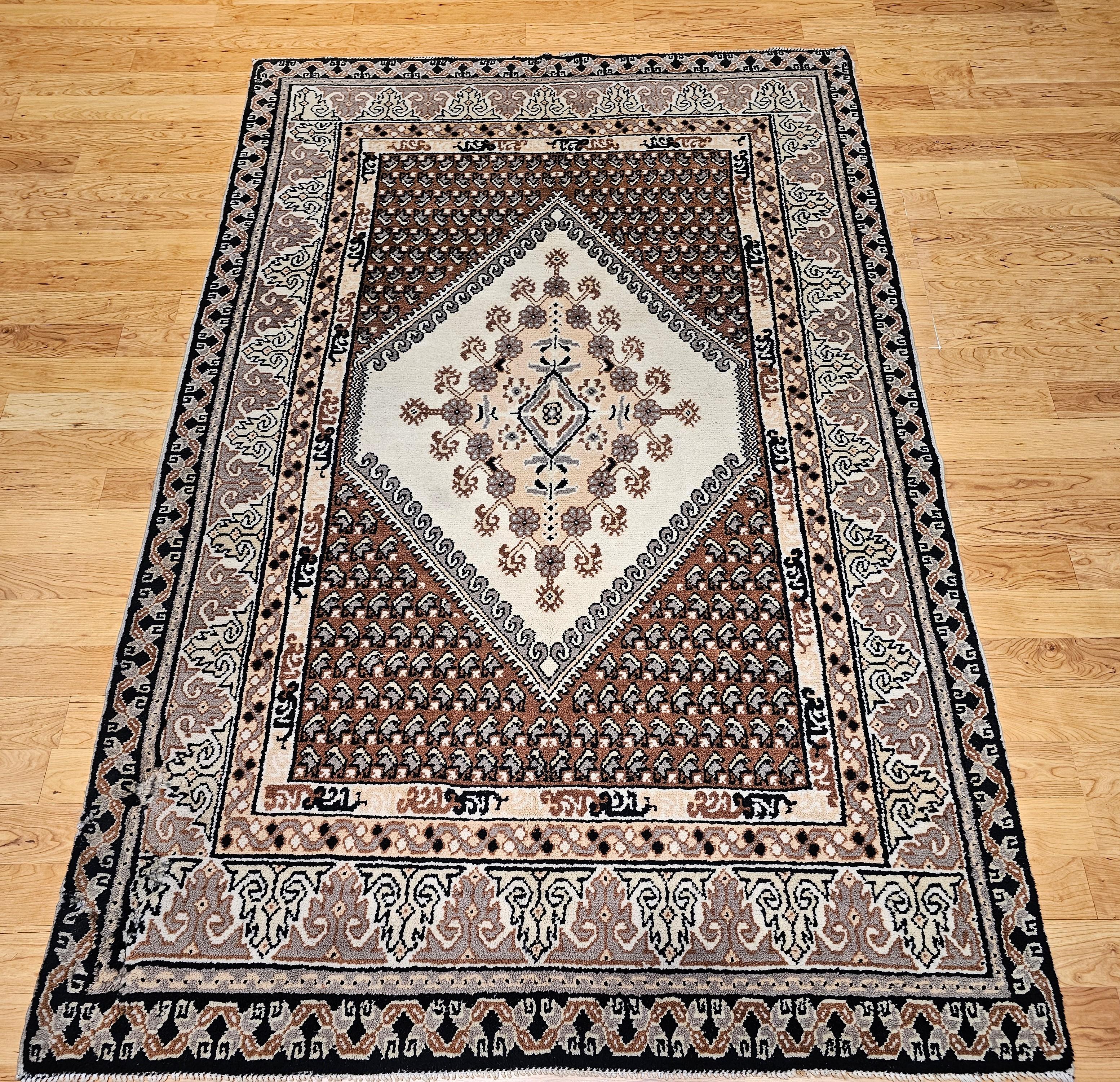 Vintage Moroccan room size rug in a geometric pattern in ivory, brown, chocolate, and gray.  This Moroccan rug has a central medallion in ivory and brown with corners containing paisley designs in chocolate color.  The border has a geometric pattern