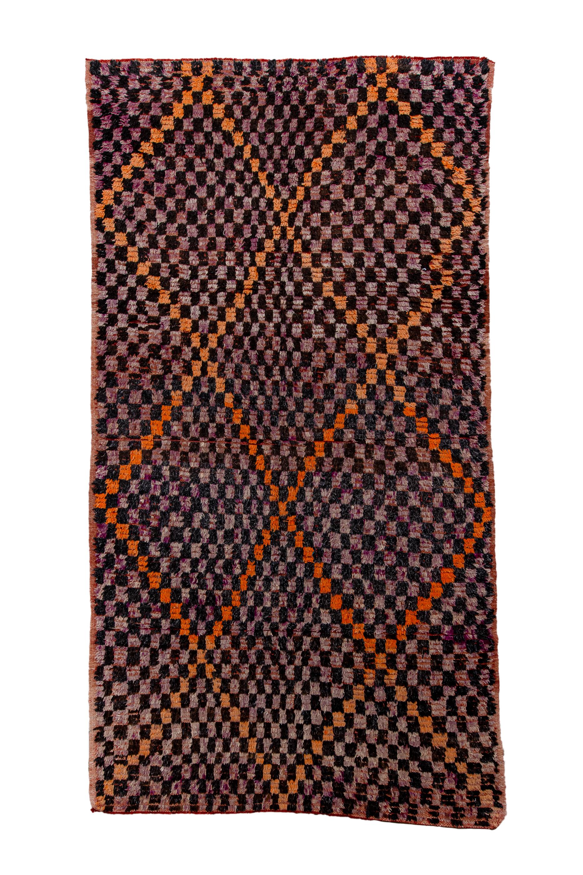 This coarsely-knotted tribal carpet shows  an allover  charcoal and  blue-grey  quasi-chessboard, structured by a broad tangerine lozenge lattice  in the same style. No borders and the tangerine stepped lattice forms triangles at one end, and along