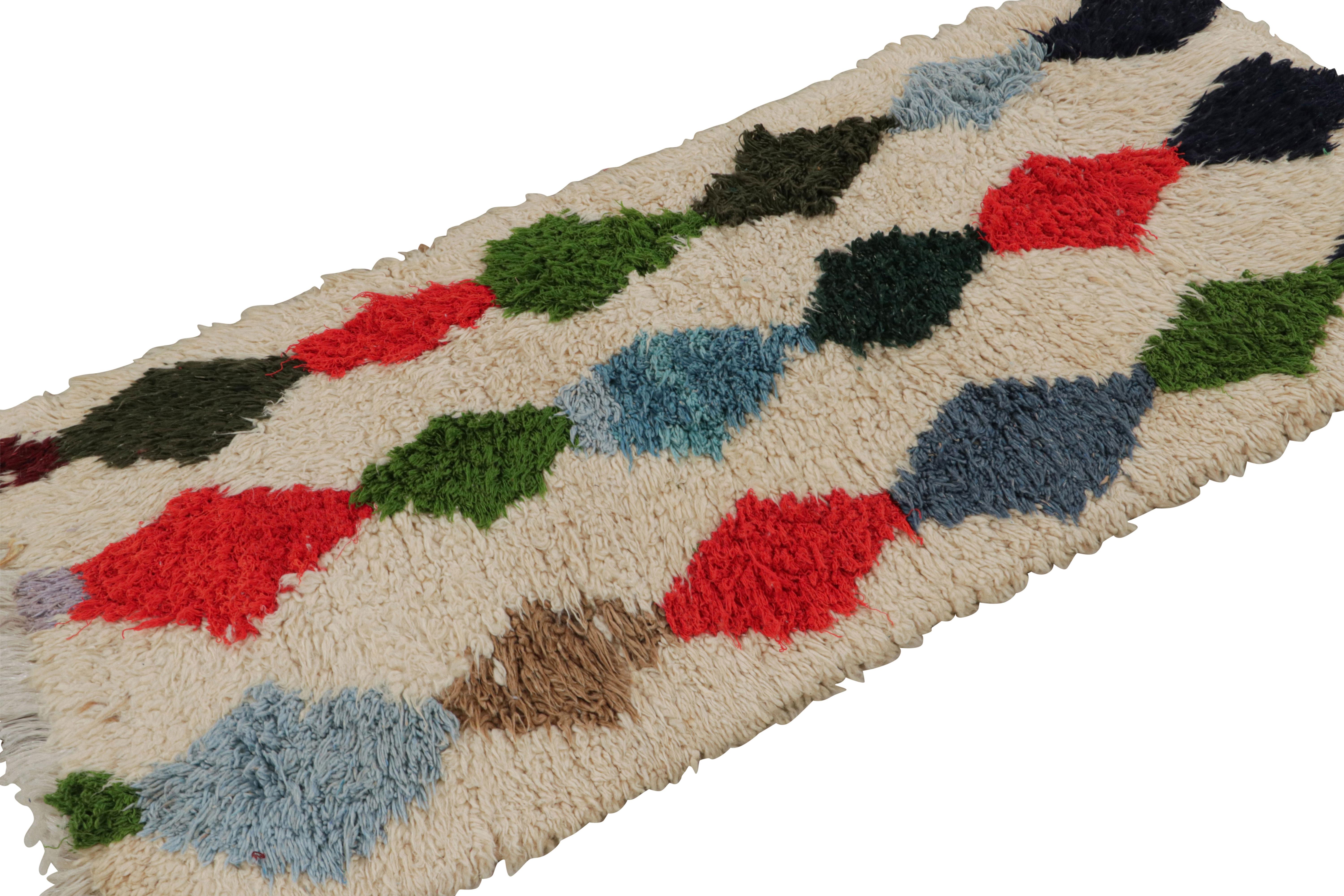 Hand-knotted in wool circa 1950-1960, this 2x6 vintage Moroccan runner rug in beige, with polychromatic diamond patterns, hails from the Azilal tribe.  

On the Design: 

This is an exemplary piece of the playful, bright nature and textural beauty