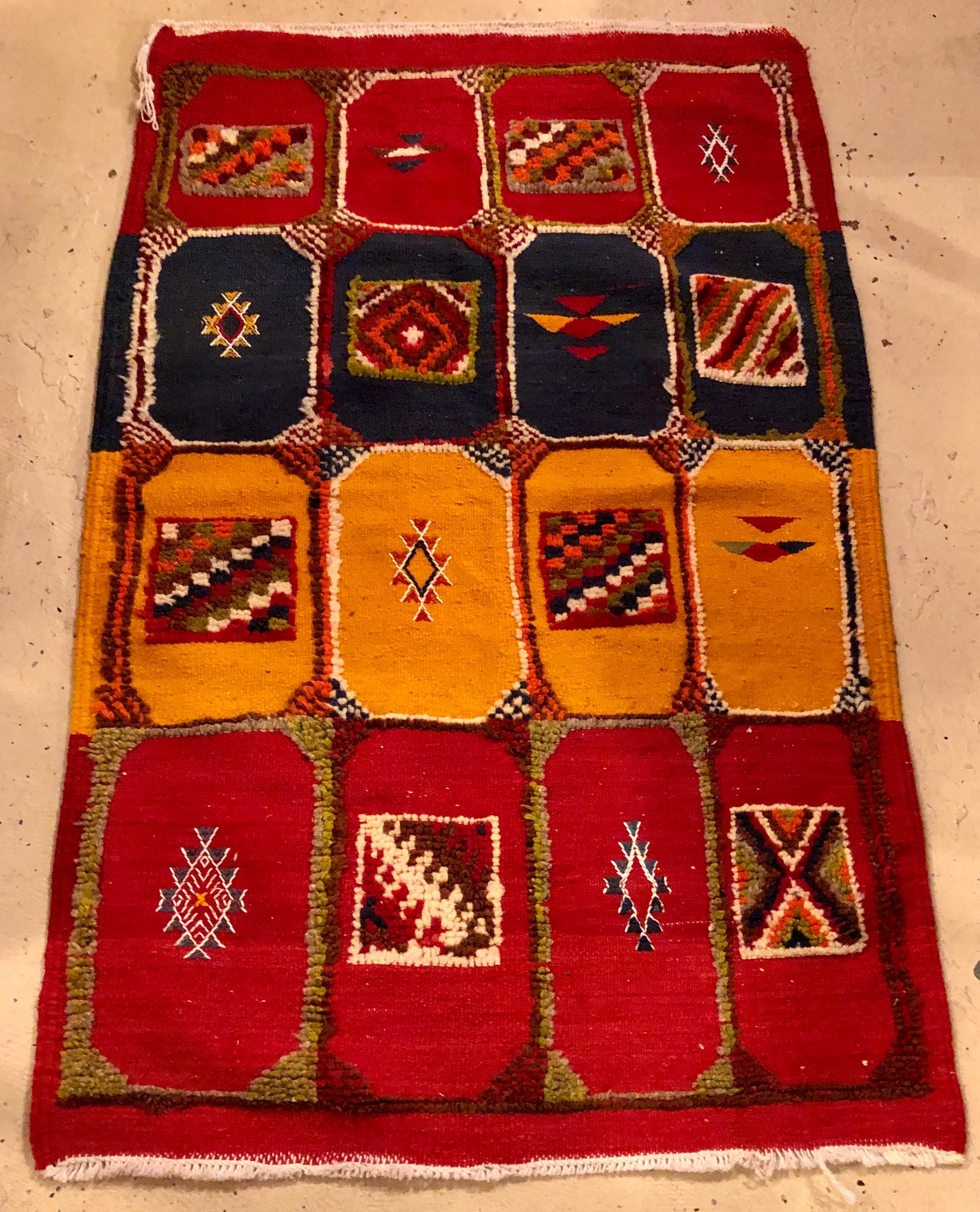 A stunning vintage Moroccan tribal berber rug handwoven of sheep wool in deep and vivid all-natural vegetable dyes. The rug features wonderfully absorbing geometric and abstract patterns alternate with Berber designs elements within a series of