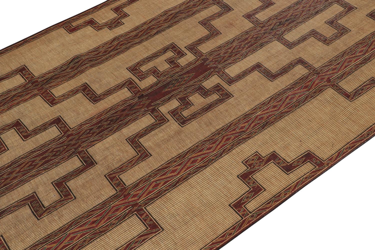 This vintage Moroccan gallery runner is a 7x13 Tuareg mat from the nomadic tribe of the same name. Handwoven with reeds and leather circa 1950-1960, its natural materials enjoy warm beige undertones with rich burgundy geometric patterns. 

On the