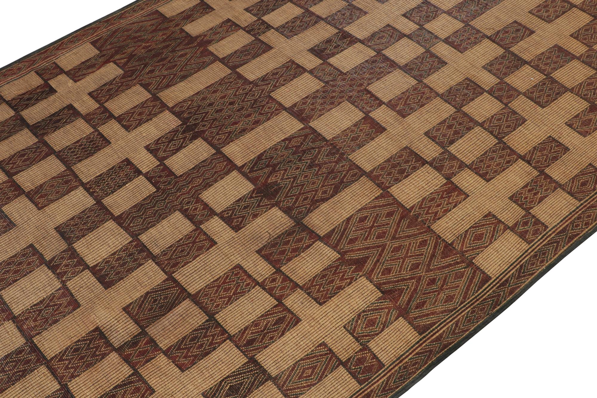 This vintage Moroccan gallery runner is an 8x14 Tuareg mat from the nomadic tribe of the same name. Handwoven with reeds and leather circa 1950-1960, its natural materials enjoy warm beige-brown undertones, and its design plays red squares with