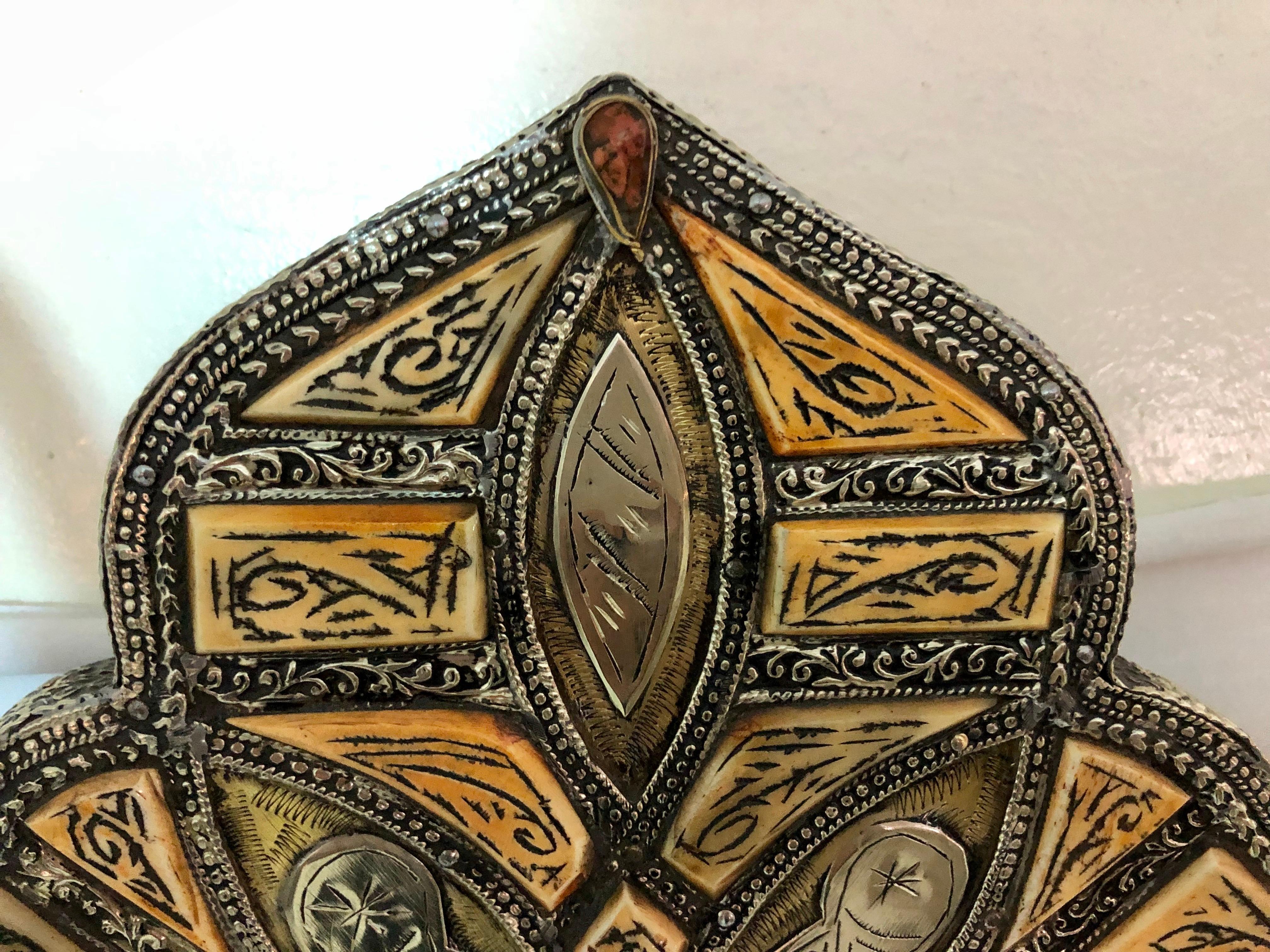 Miroir de courtoisie ou miroir mural marocain antique et arqué, fabriqué à la main en os naturel et gravé de magnifiques motifs tribaux. Le cadre du miroir est incrusté dans du laiton qui présente une belle décoloration due au vieillissement. Tout