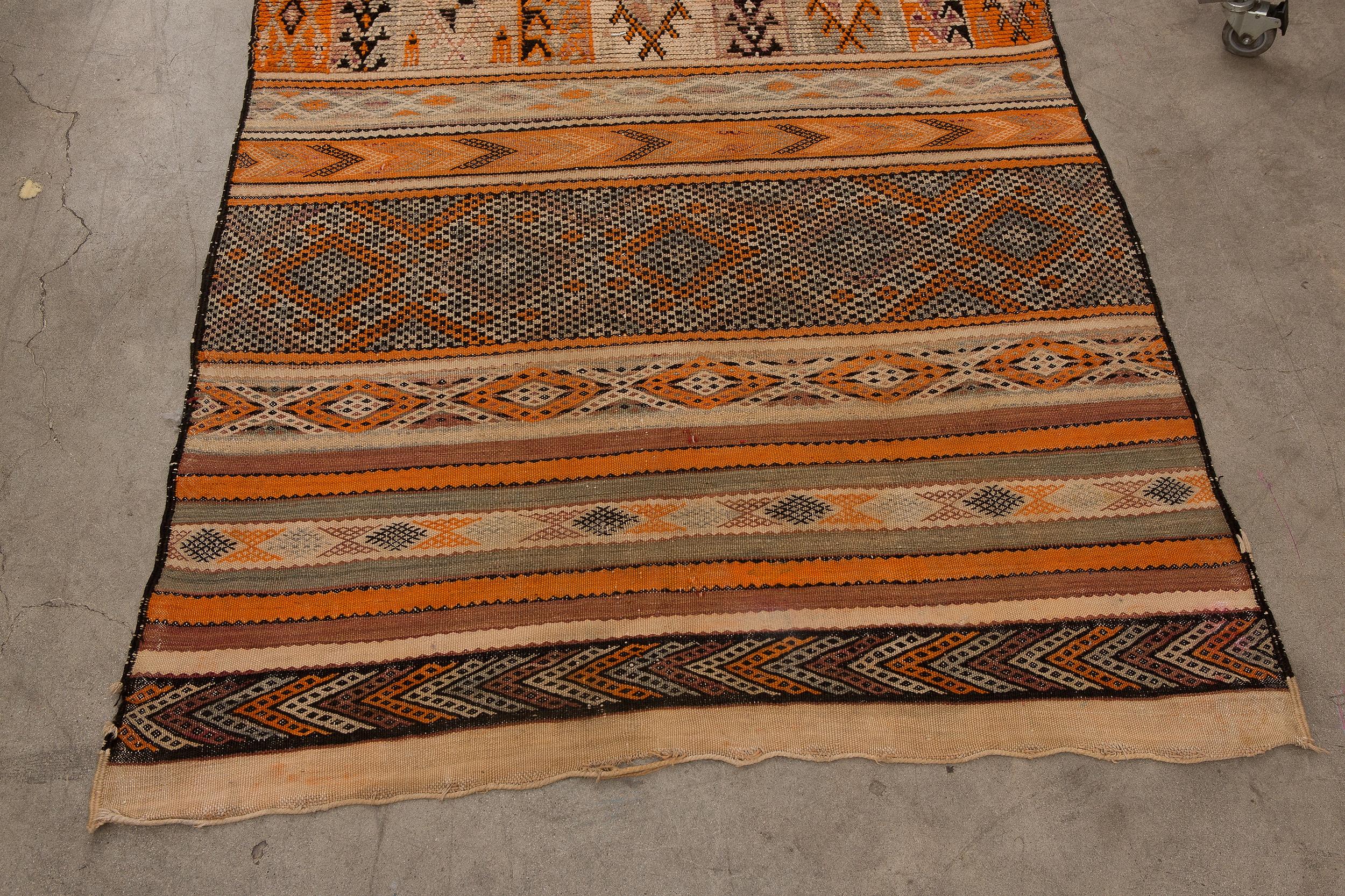 Handmade by Berber women from the Middle Atlas Mountains of Morocco, this flat-weave Kilim rug is woven primarily from wool with the addition of decorative cotton. This piece consists of traditional sets of patterned bands, geometric designs,