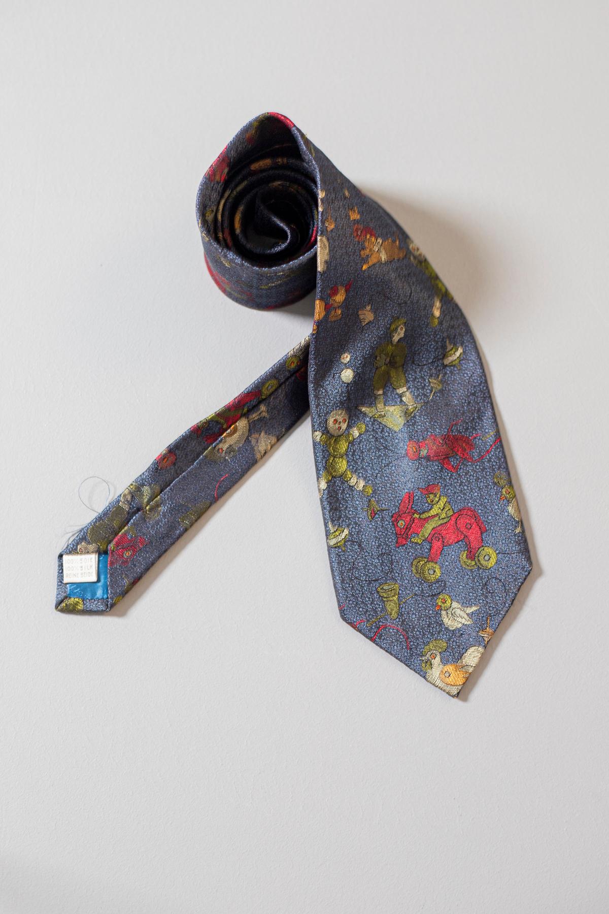 This Moschino all-silk tie is very special: on a dark blue background are embroidered different figures that look like animals and toys. You do not want to miss this tie if you are a real Moschino fan. This accessory is perfect for funny and