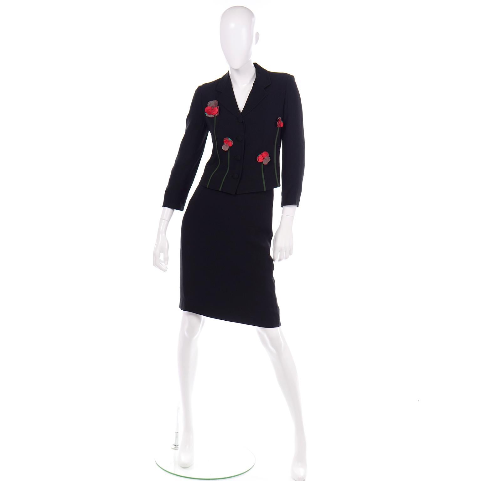 This vintage 1990's Moschino black skirt suit has beautiful iridescent silk flower applique on the jacket. The colors of the applique detail are green and red. 
The jacket is cropped and fitted with shoulder pads for structure. There are fabric