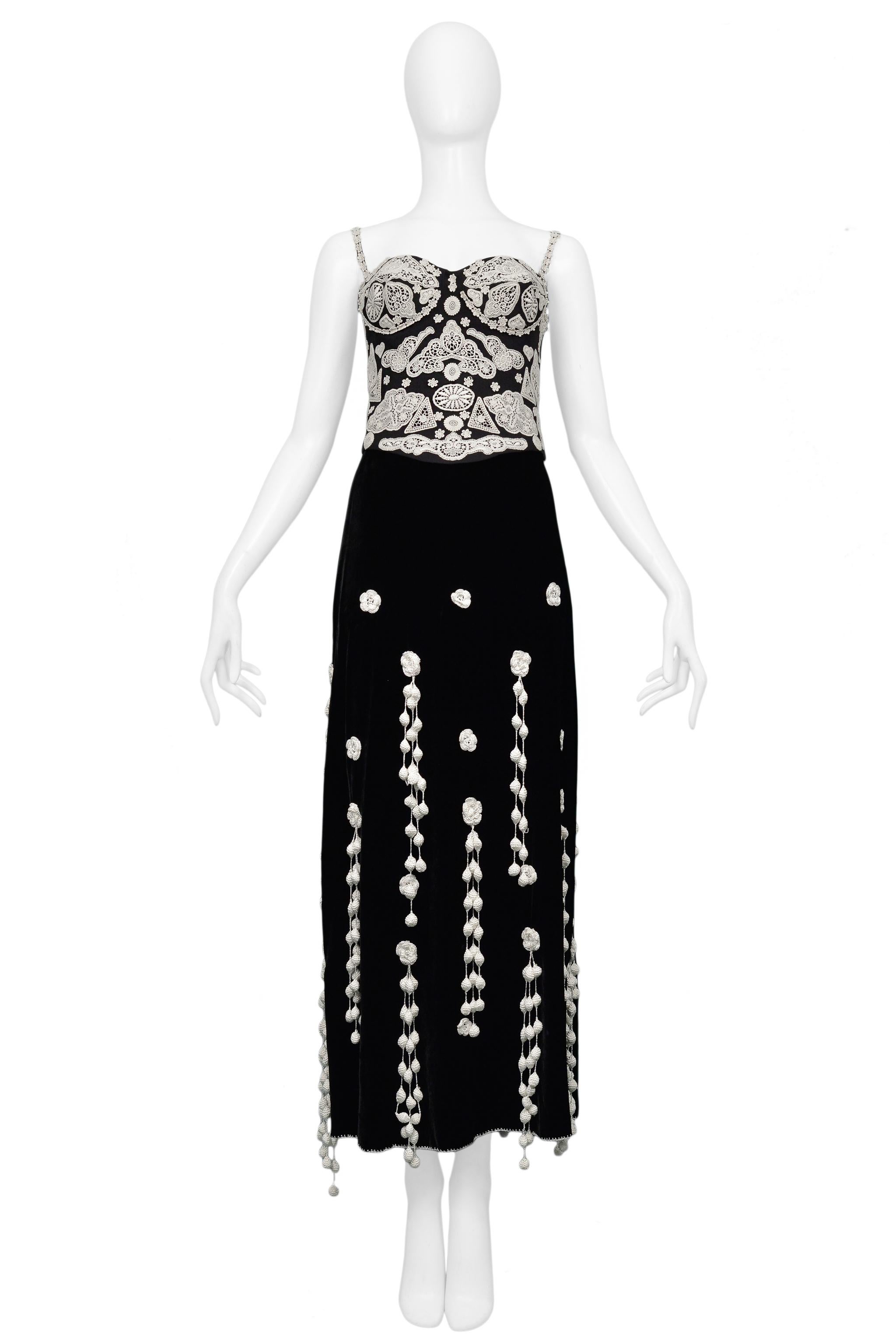 Resurrection Vintage is excited to offer a vintage Moschino black velvet top and skirt ensemble with off white crochet appliques. The top features a classic bustier silhouette, lace overlay, skinny straps, and a side zipper. The velvet skirt