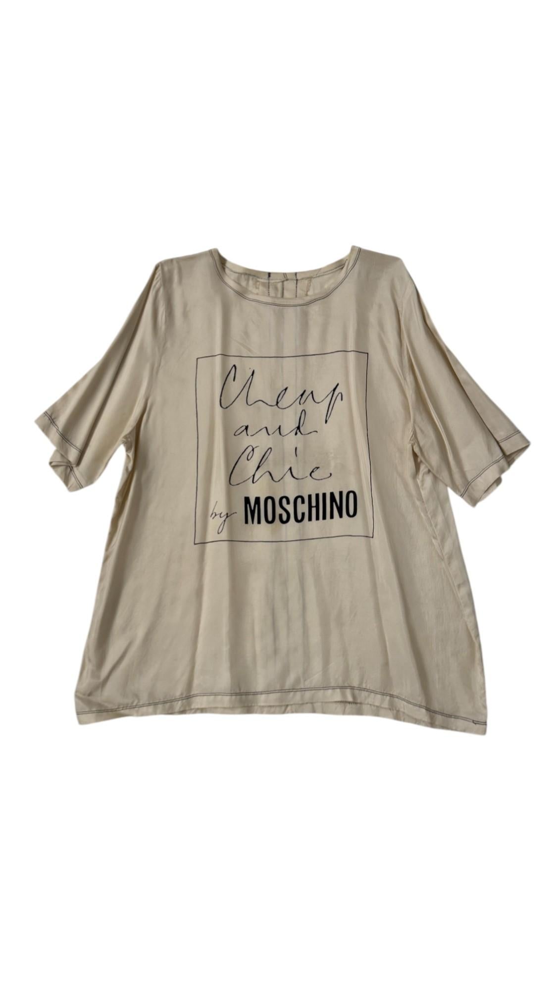 Lassen Sie sich von der verspielten Eleganz von Moschino aus den 1990er Jahren inspirieren - mit diesem seltenen Seidentop in Übergröße aus der kultigen Cheap and Chic-Linie. Das Hemd aus leuchtender, champagnerfarbener Seide zeichnet sich durch