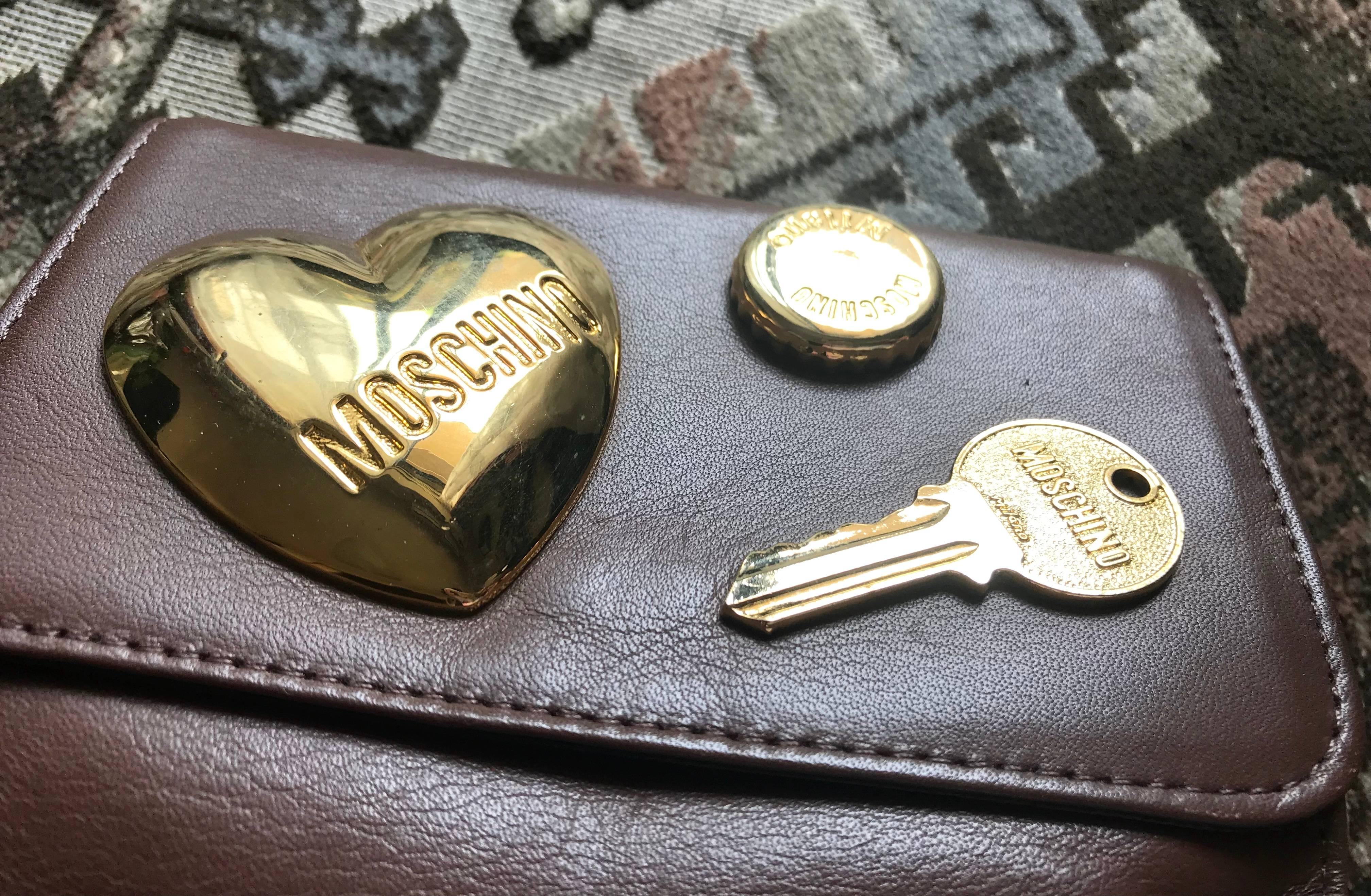 ***This is pouch only. No belt.***
Vintage MOSCHINO chocolate brown leather clutch pouch with large golden heart and key motifs. With your own belt, it can be fanny pack. Chic and Mod.

This is a vintage MOSCHINO, cute shape chocolate brown leather