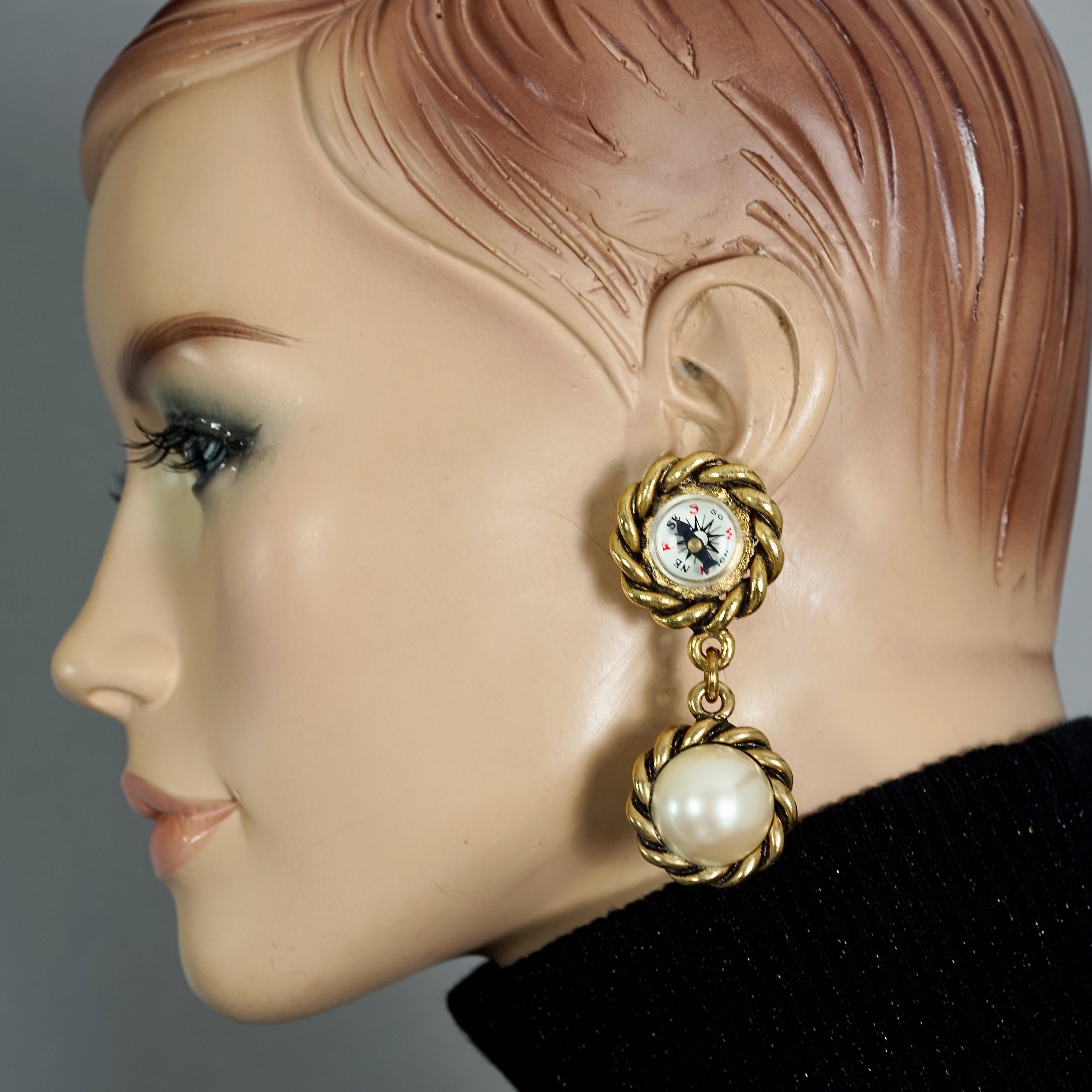 Vintage MOSCHINO Compass Pearl Novelty Dangling Earrings

Measurements:
Height: 2.75 inches (7 cm)
Width: 1.10 inches (2.8 cm)
Weight per Earring: 22 grams

Features:
- 100% Authentic MOSCHINO.
- Compass novelty dangling earrings.
- Clip back