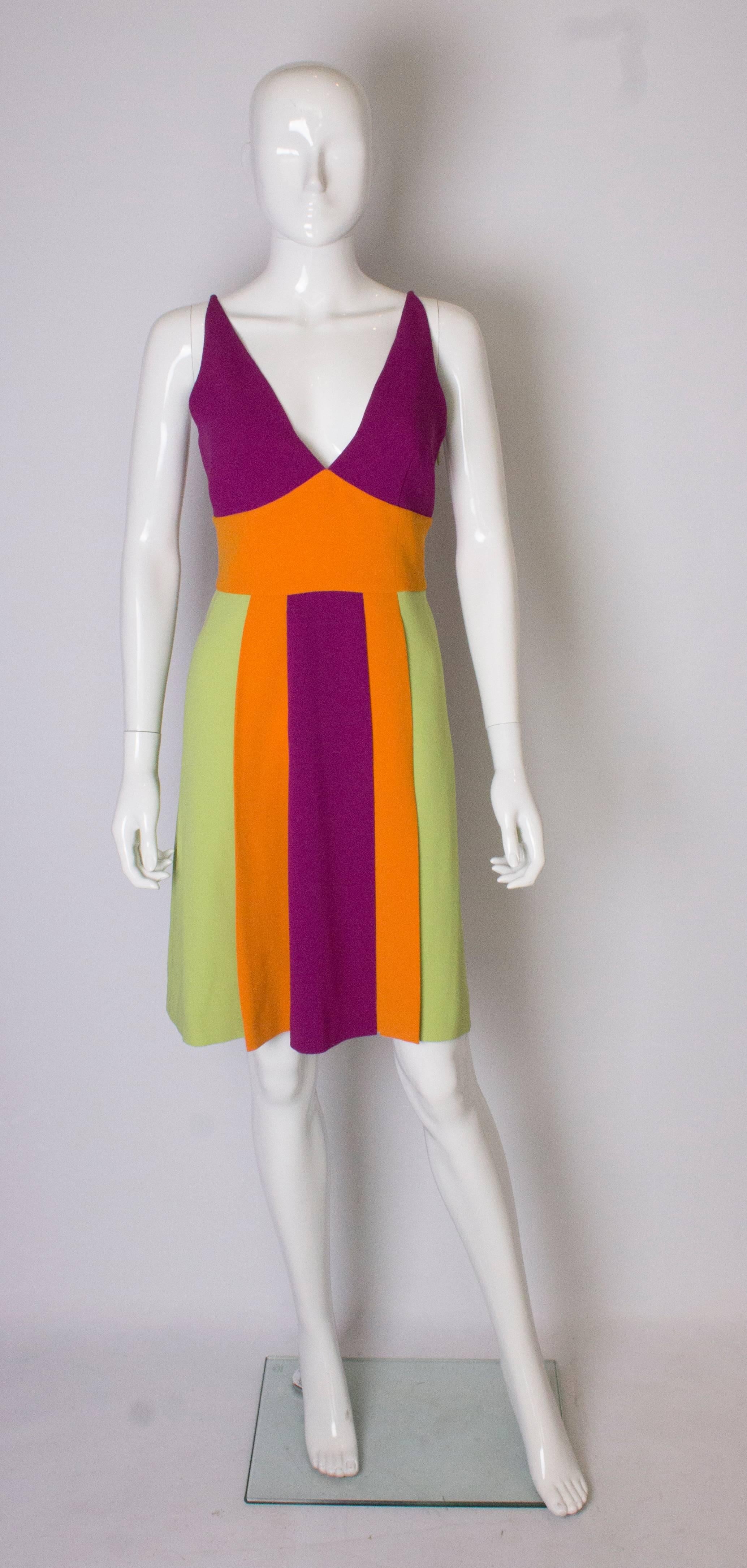 A vintage runway collection dress by Moschino , Cheap and Chic.  The dress has a v neckline, front and back , with a side zip and is fully lined. The pleated skirt is in  green, orange and purple..
