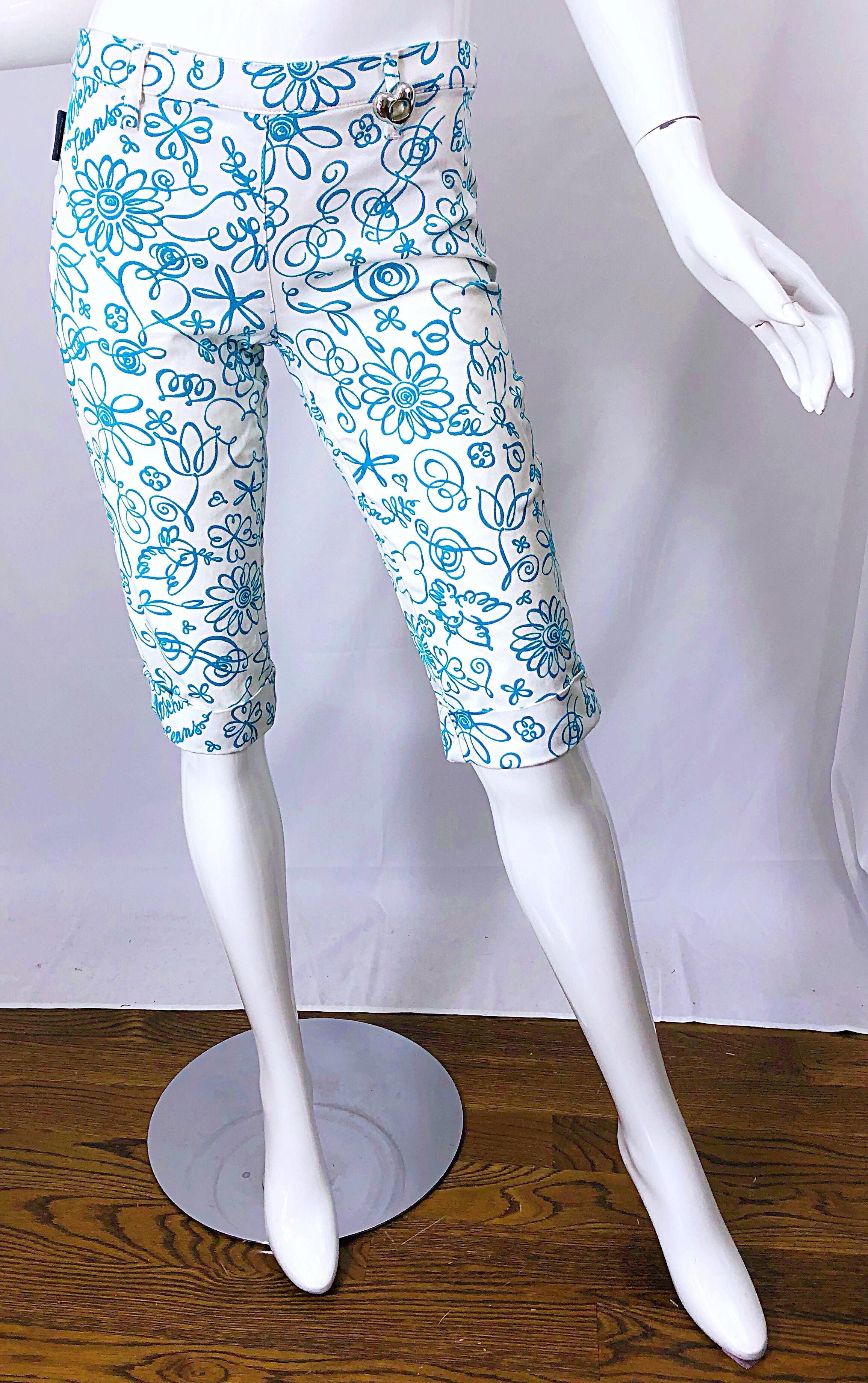 Stylish vintage MOSCHINO 1990s novelty print clam digger shorts! Features a white background with teal / turquoise blue graffiti prints throughout. Silver heart metal at left side belt loop. Fun prints of birds, hearts, stars, music notes, etc.