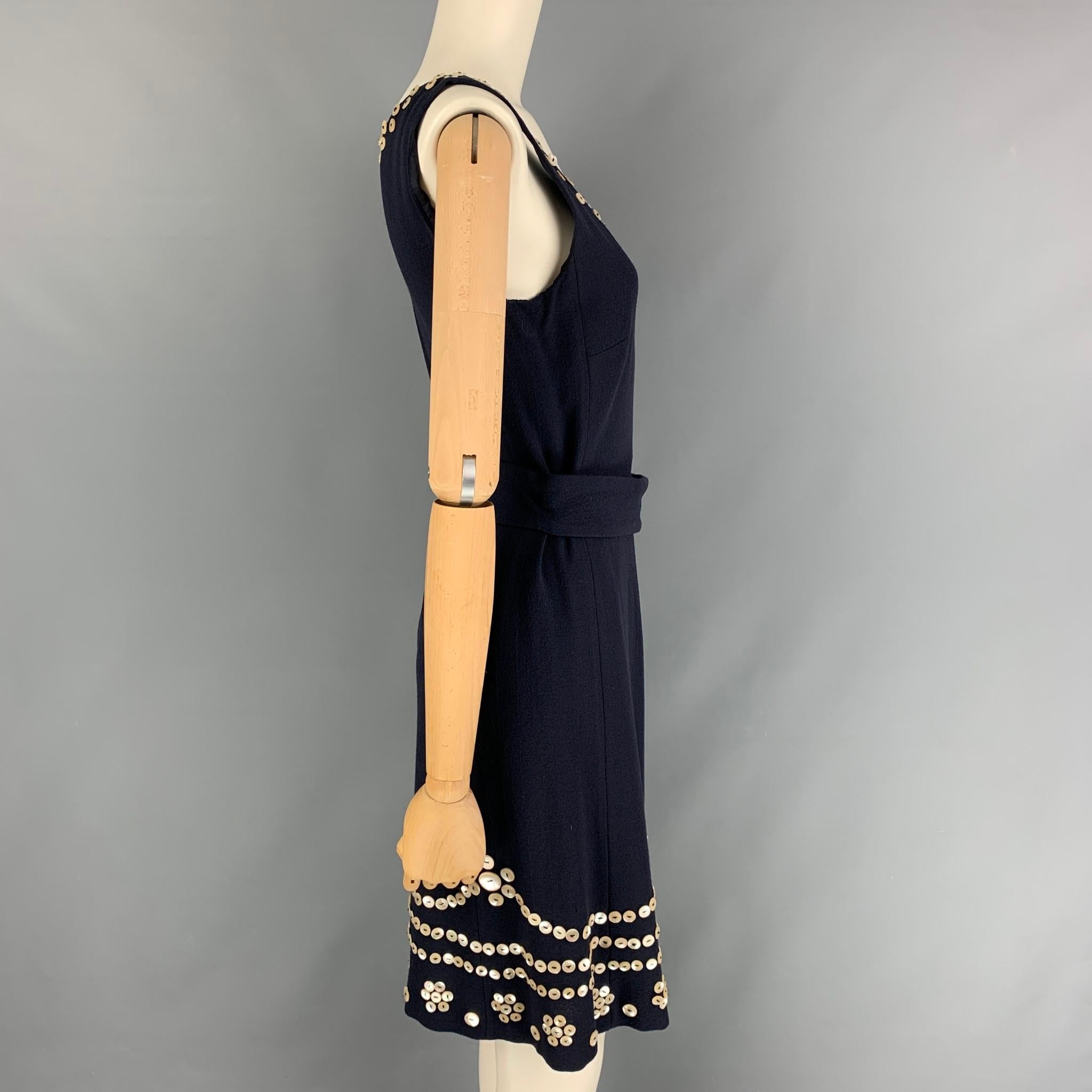 Vintage MOSCHINO dress comes in a navy wool with a slip liner featuring a shift style, belt strap, buttoned applique details, and a side zip up closure. Made in Italy.

Very Good Pre-Owned Condition.
Marked: I 42 / D 38 / F 38 / GB 10 / USA