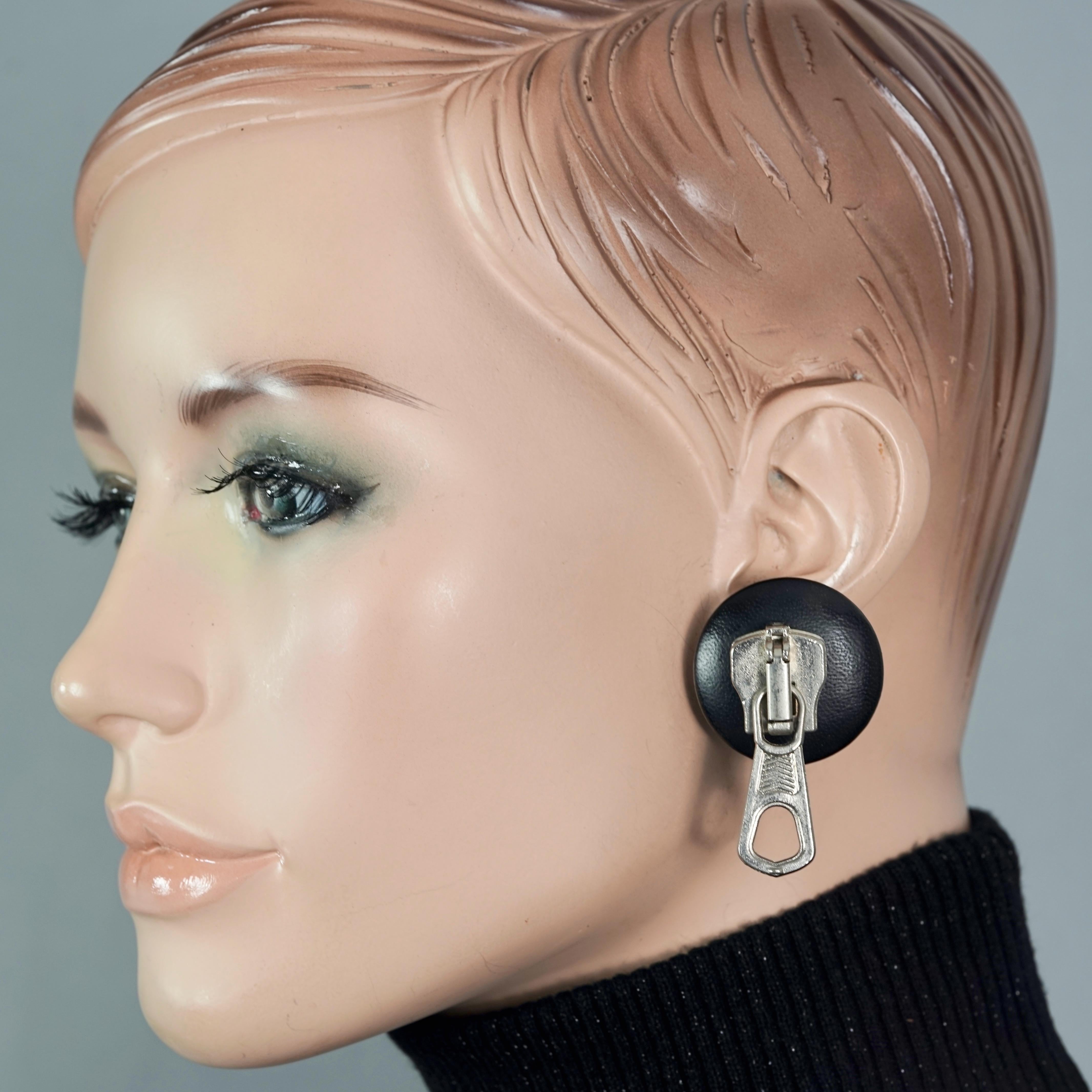 Vintage MOSCHINO Zipper Leather Disc Novelty Earrings

Measurements:
Height: 1.89 inches (4.8 cm)
Width: 1.26 inches (3.2 cm)
Weight per Earring: 16 grams

Features:
- 100% Authentic MOSCHINO.
- Zipper on black leather disc earrings.
- Silver tone