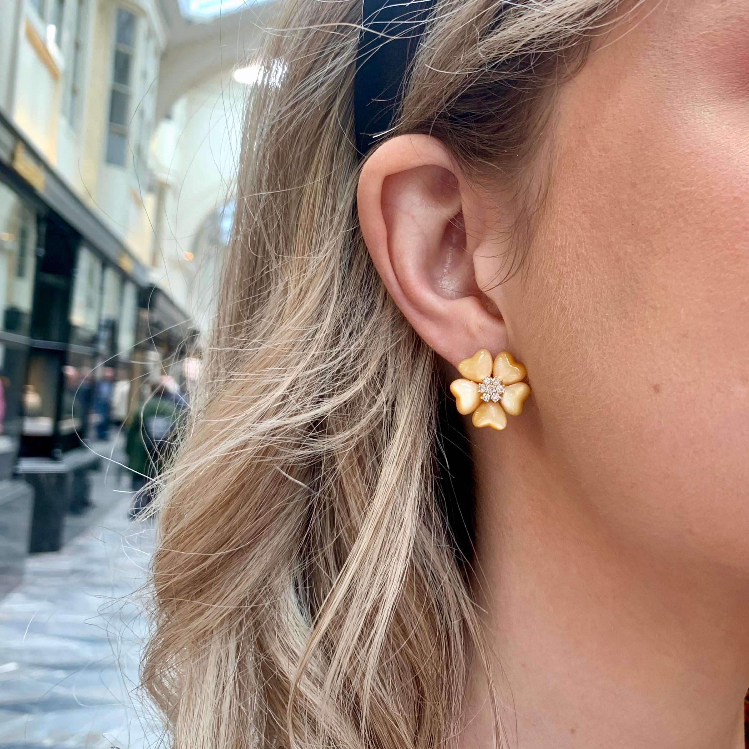 A beautiful pair of vintage diamond and mother of pearl flower earrings set in 18k yellow gold.

The earrings depict an elegant five petaled flower comprised of carved pieces of lustrous mother of pearl. Set centrally is a fine cluster of round