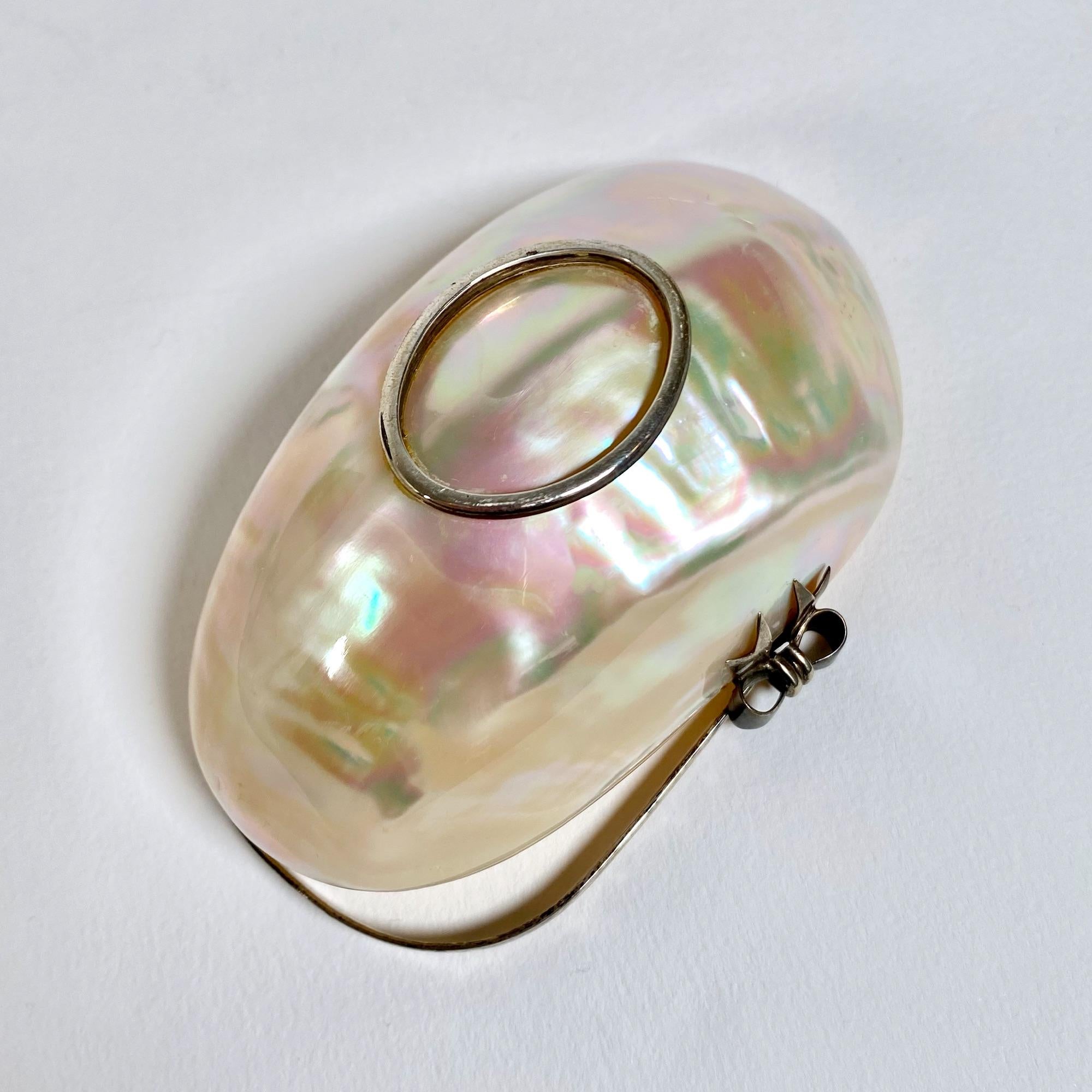 This exquisite salt and pepper set, dating back to the 1970s, is a stunning combination of mother-of-pearl and silver craftsmanship. Each piece measures 10.5 cm and 11 cm in length, with a width of 6 cm and a height of 9 cm, including the elegant