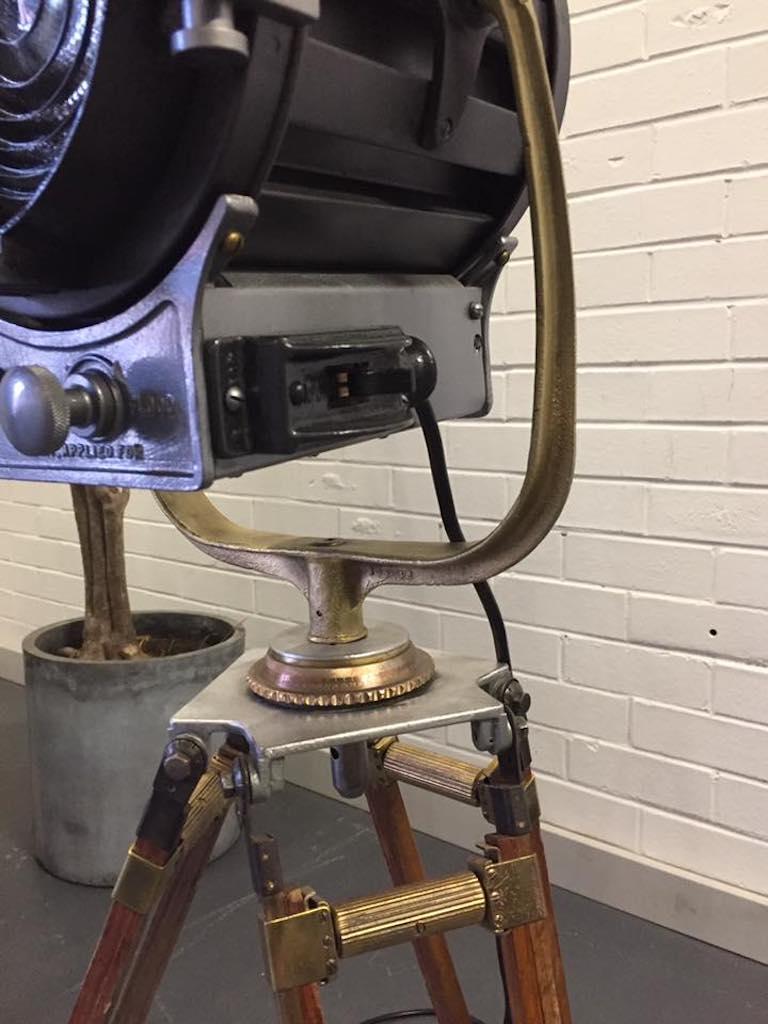 A rare collectable antique movie spotlight with expandable wooden tripod base. 

Details
- Era: Industrial
- Date of manufacture: 1950s
- Materials: Cast aluminum and wood
- Condition: Excellent, strong and sturdy.
- Wear: Wear consistent with age