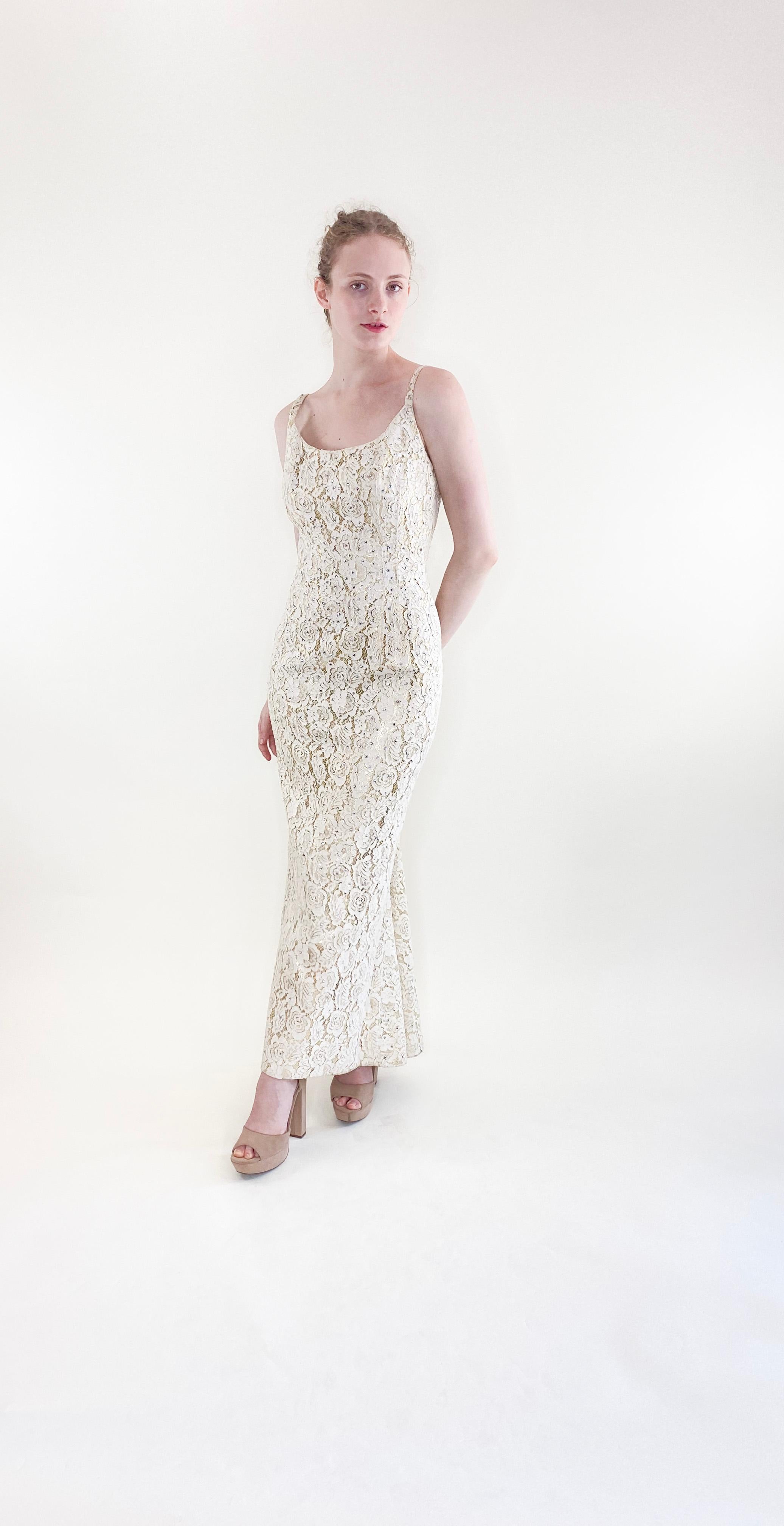 Make a statement with the vintage elegance of the Mr. Blackwell 1960's Lace & Rhinestone Gown. This stunning wedding gown features intricate white and gold lace with sparkling rhinestones, designed to accentuate your curves in a mermaid fit. Embrace