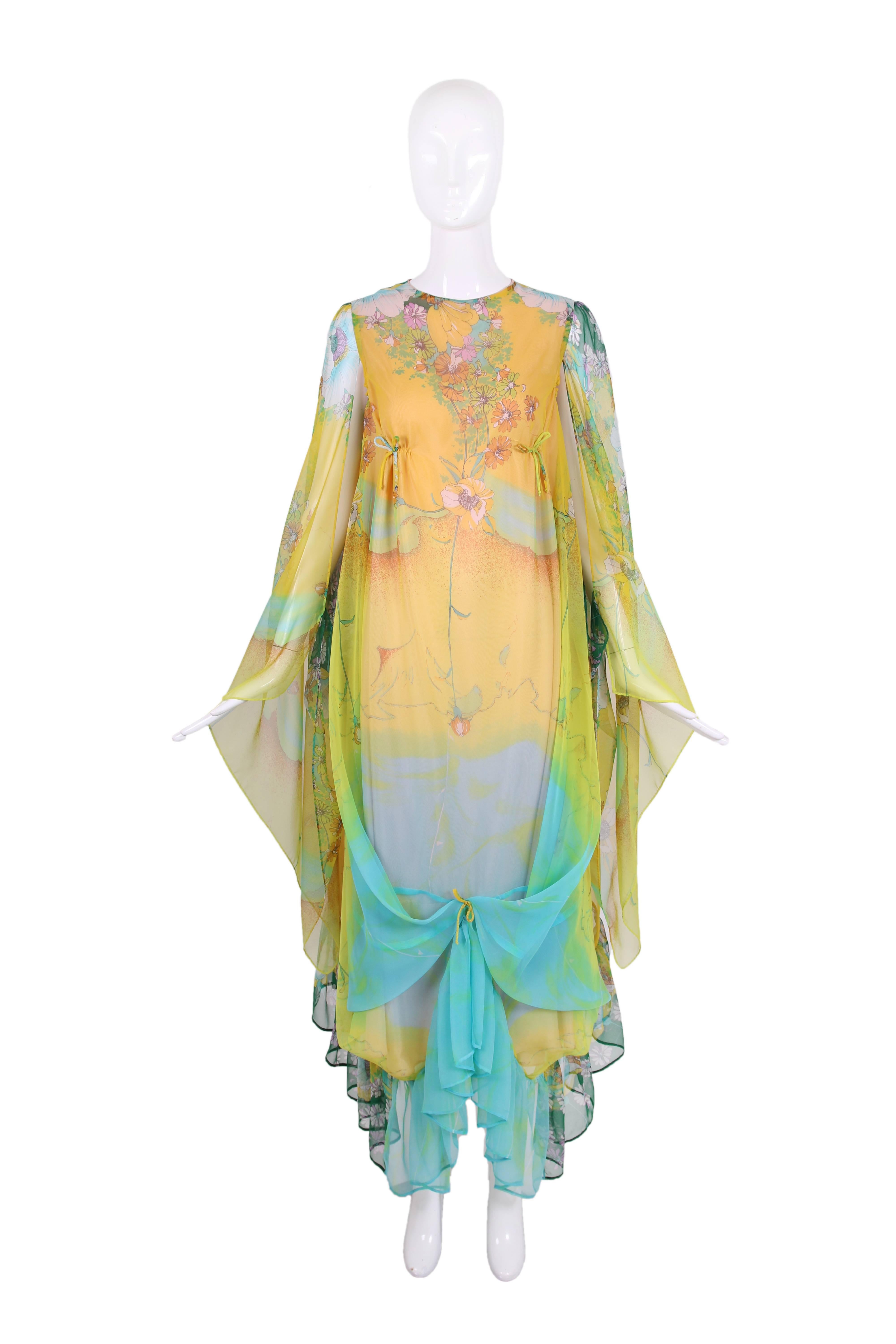 Vintage Mr. Blackwell silk floral printed caftan in yellow, blue, orange, green, and purple. This caftan features small ties at bust, along back closure, and one in the center at knee-length. Ruffle hem and lined in pink silk. In excellent