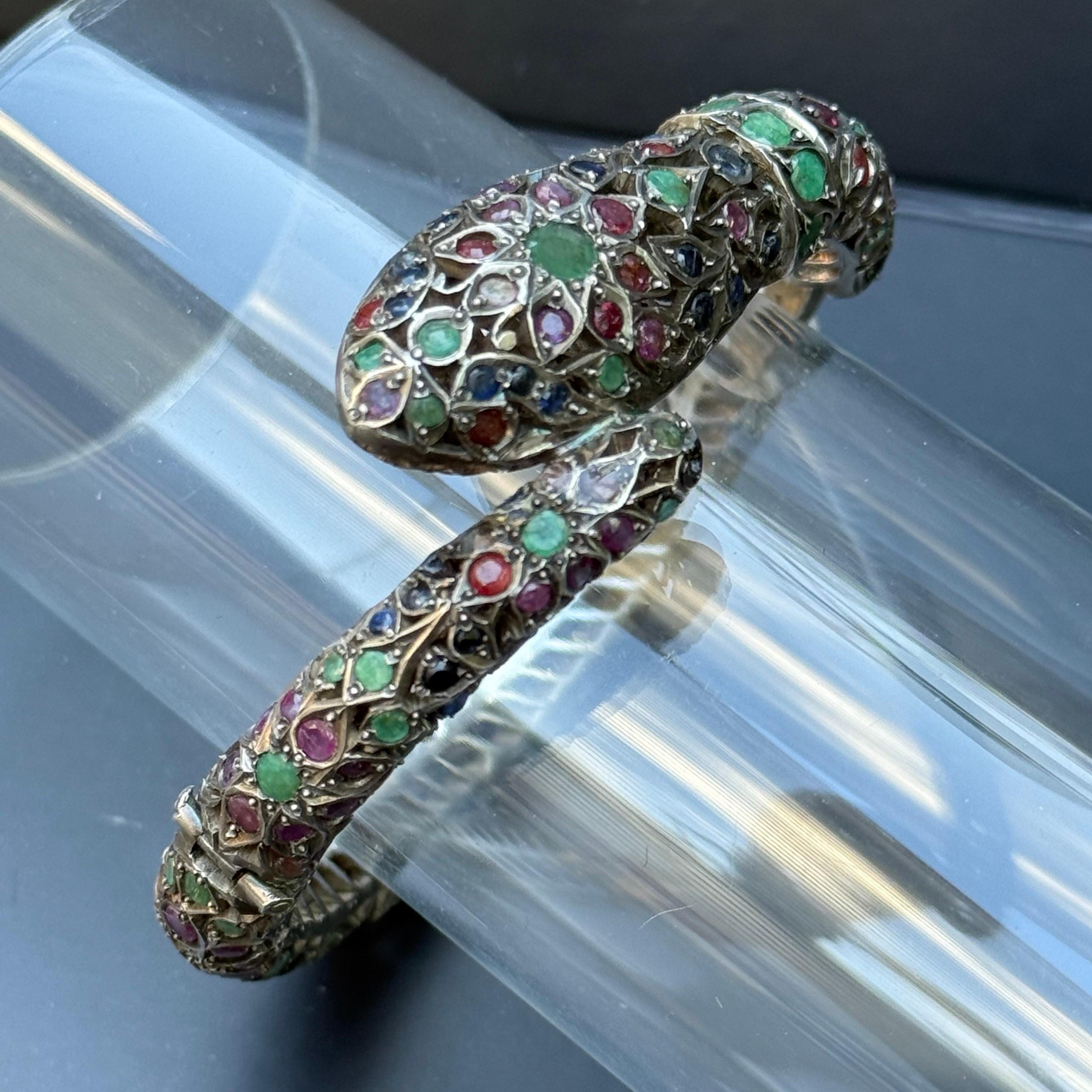 Questo bracciale vintage con cerniera è realizzato in argento e ha la forma di un serpente arrotolato stilizzato, un simbolo duraturo di protezione, saggezza e rinascita. Il bracciale è impreziosito da gemme autentiche, tra cui zaffiro, rubino,