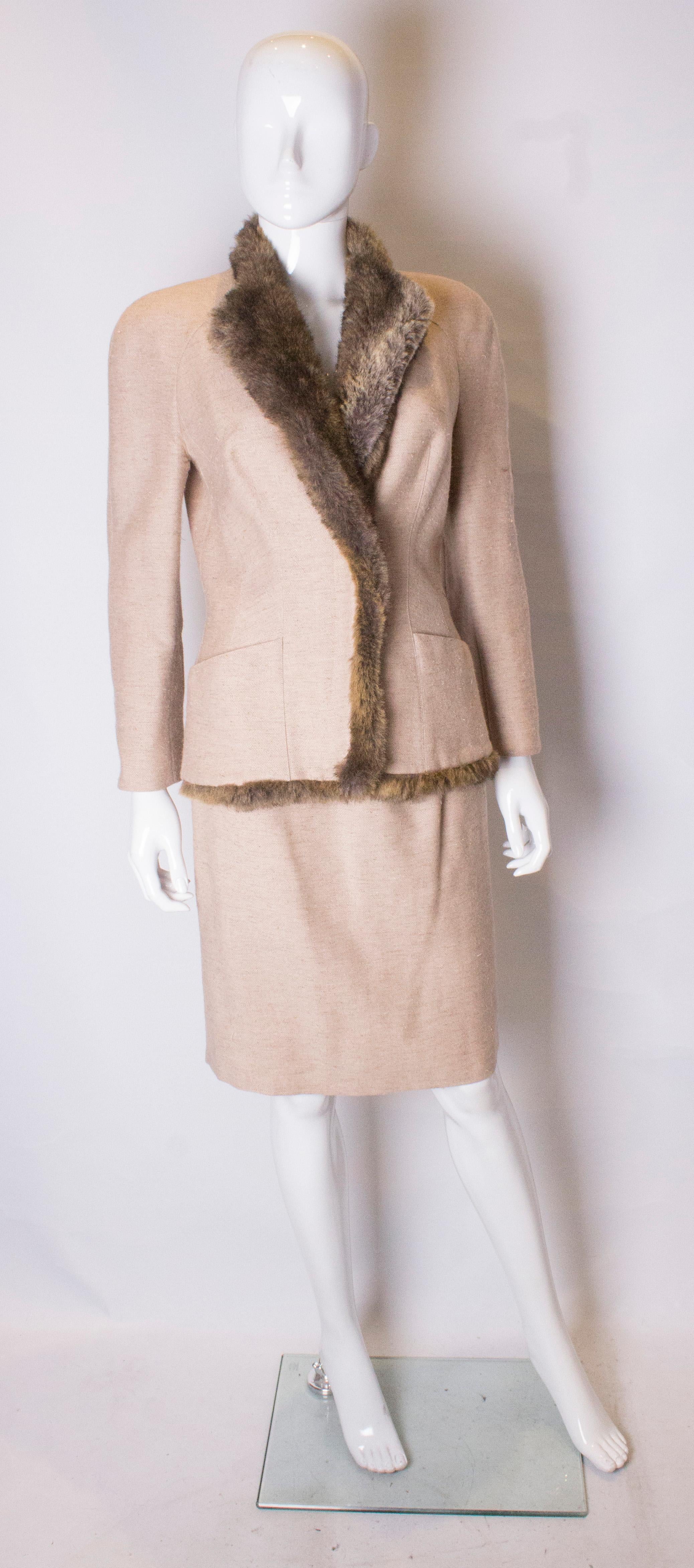 Un tailleur jupe vintage chic de Mugler. Le costume est fait d'une jolie laine couleur biscuit avec une décoration en fausse fourrure.  La veste est dotée de deux poches sur le devant et d'un col et d'une bordure en fausse fourrure sur le devant et
