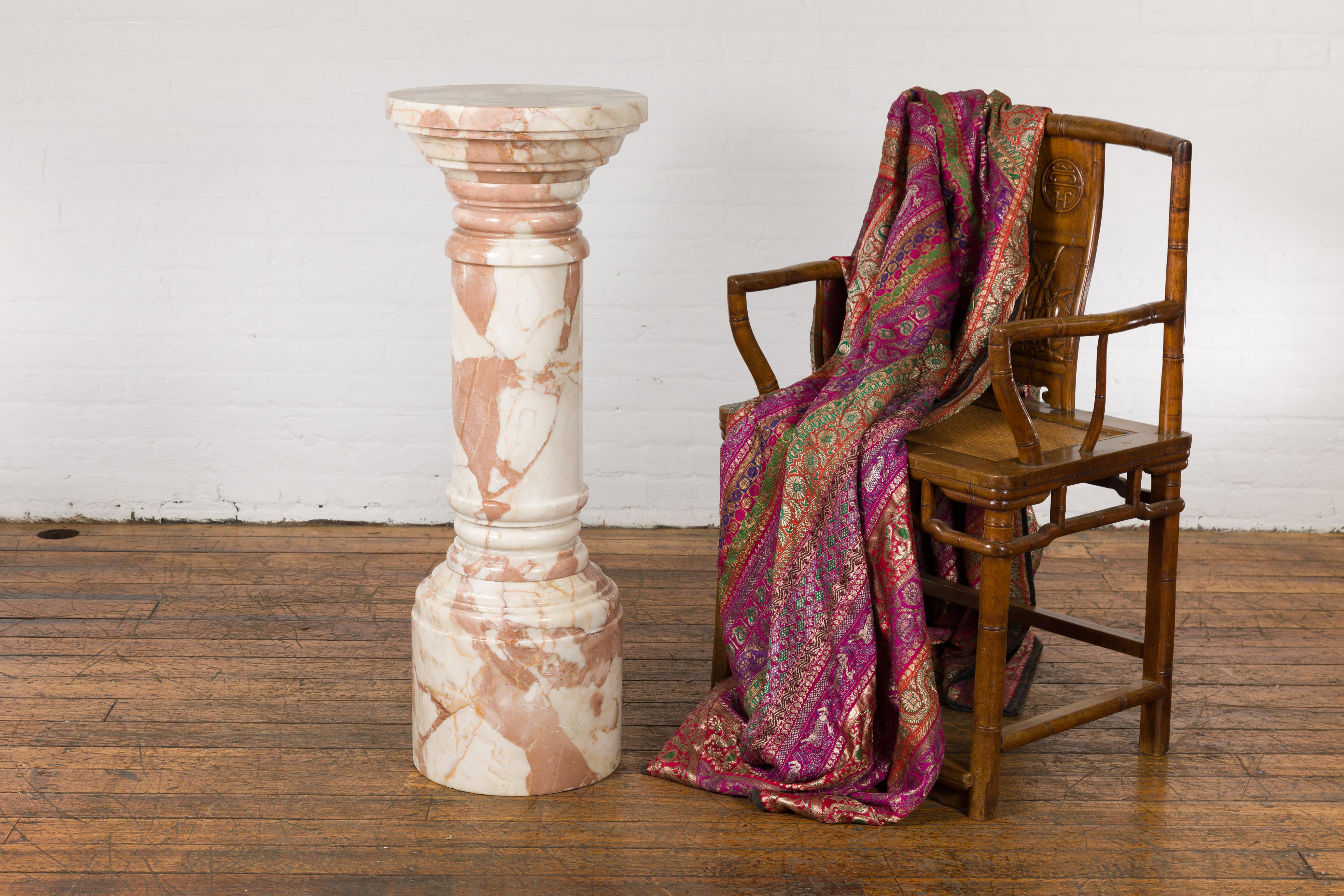 A vintage Indian pedestal from the mid-20th century, with variegated white, pink and brown marble. Emanating an aura of subtle grace, this vintage Indian pedestal from the mid-20th century is a consummate marriage of form and elegance. Crafted with