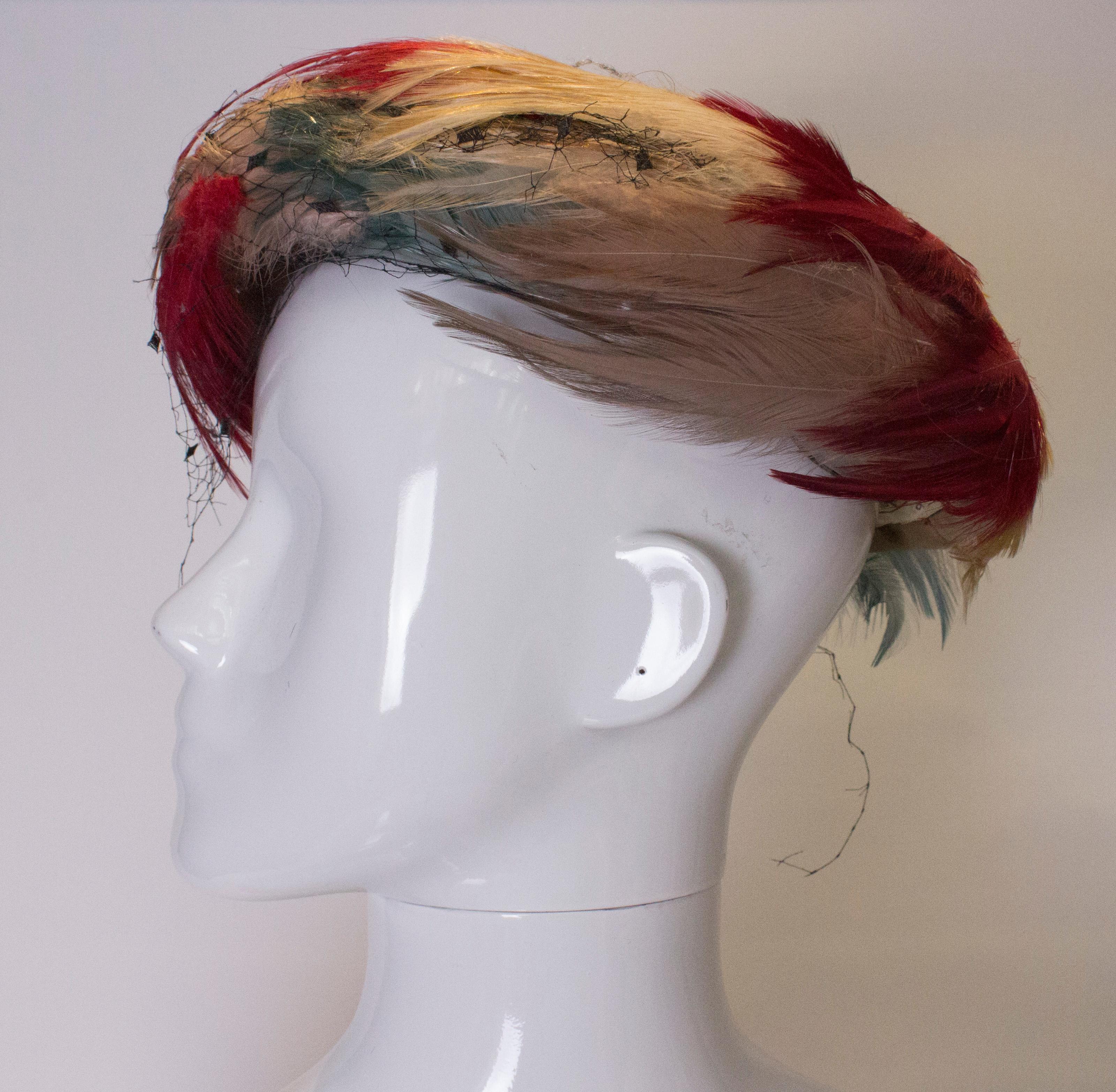 A head turning hat in multicolour feathers. The hat was made by Debenham and Freebody, and is lined with an attached veil. Inner rim measurements  23''