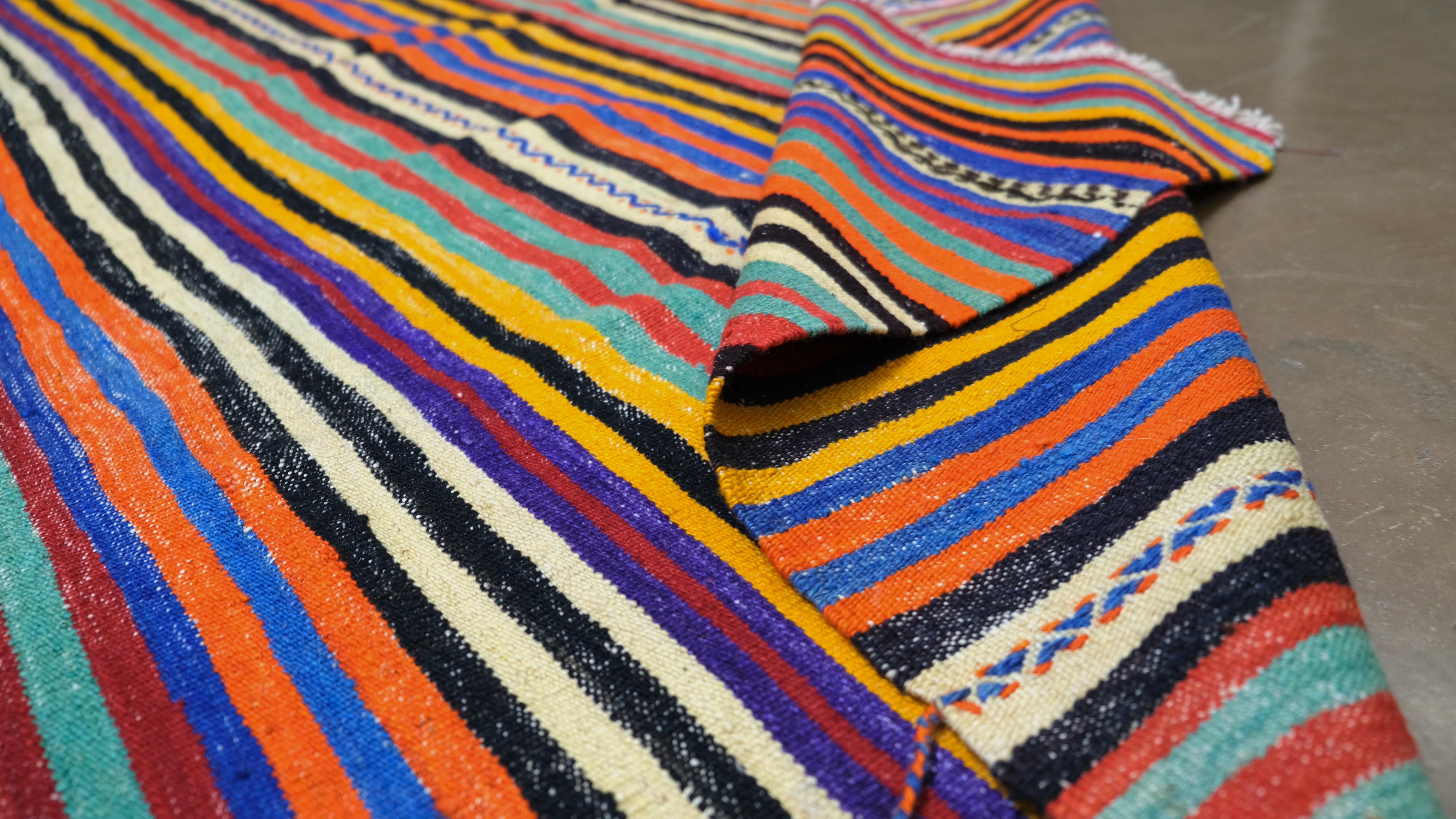 Brighten your space with this stunning vintage handwoven wool Kilim from Turkey. Featuring a vibrant array of multicoloured stripes in a captivating tribal-inspired design, this rug is an exquisite example of traditional Turkish craftsmanship. The
