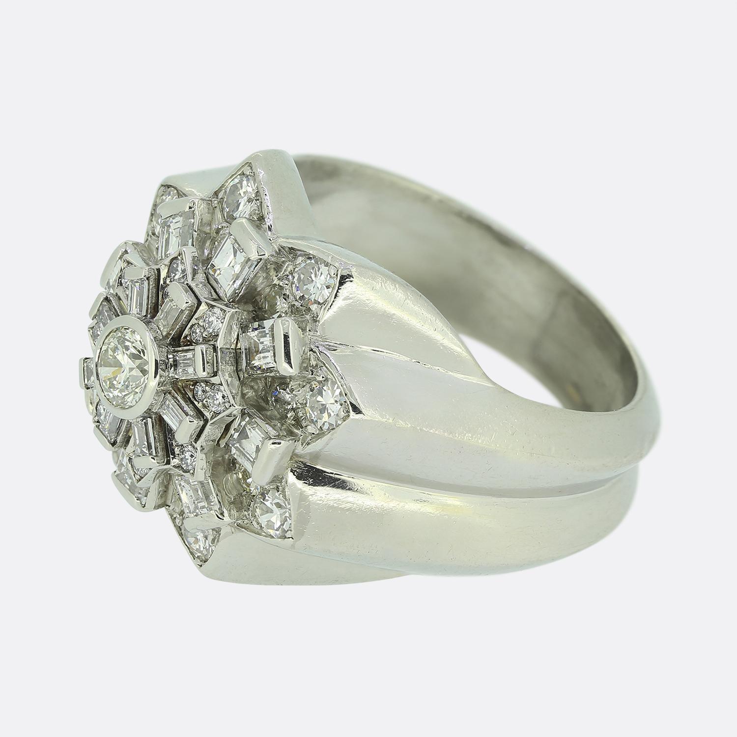 Here we have a masterfully designed cluster ring featuring a dazzling array of diamonds. The face of the ring has been crafted into the shape of an 8 pointed star whilst showcasing a round brilliant-cut white diamond at the centre. This principal