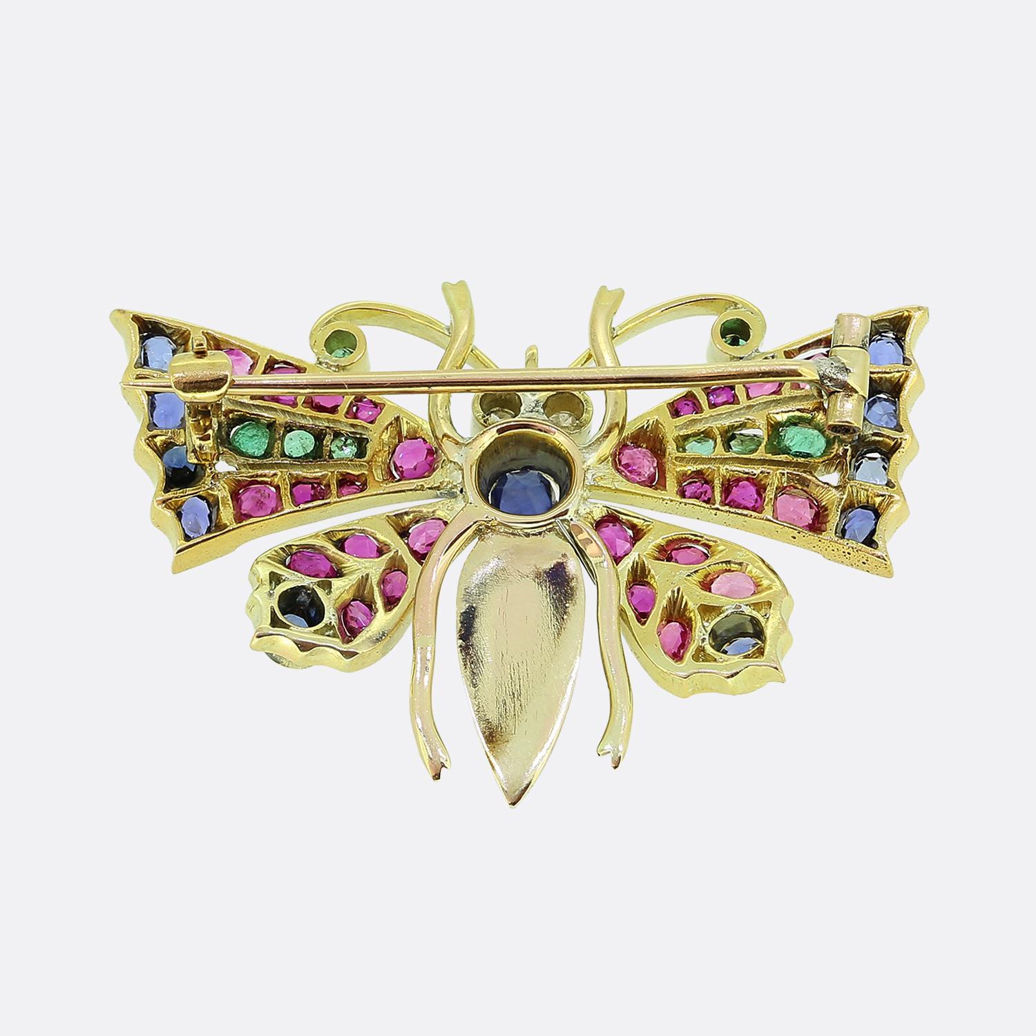 Aquí tenemos un vibrante broche de mariposa elaborado en oro amarillo de 18 ct. Una montura hecha a mano por expertos exhibe un detallado diseño de mariposa con una vibrante variedad de piedras preciosas, como zafiros, rubíes, esmeraldas y