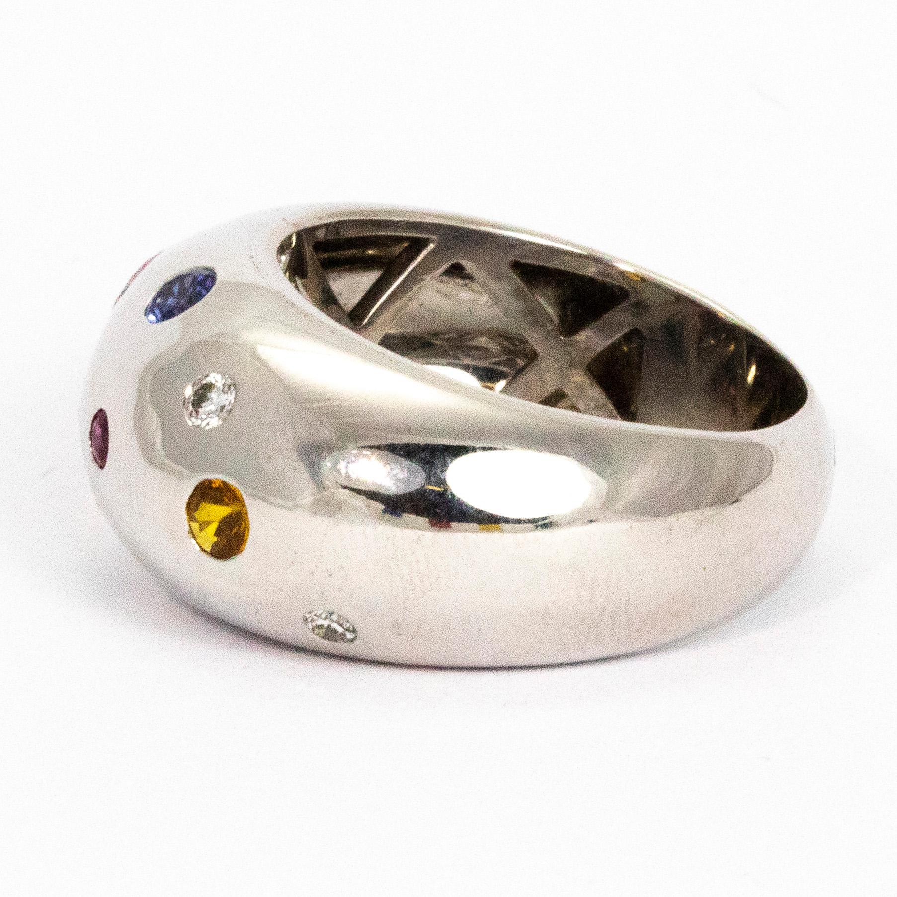 This ring holds Sapphires, Diamond, Rubies and Citrine. The multi coloured stones in this chunky 18ct white gold band are stunning. The smooth rounded band is paired perfectly with the round cut stones of all sizes. Hallmarked London 2015. 

Ring