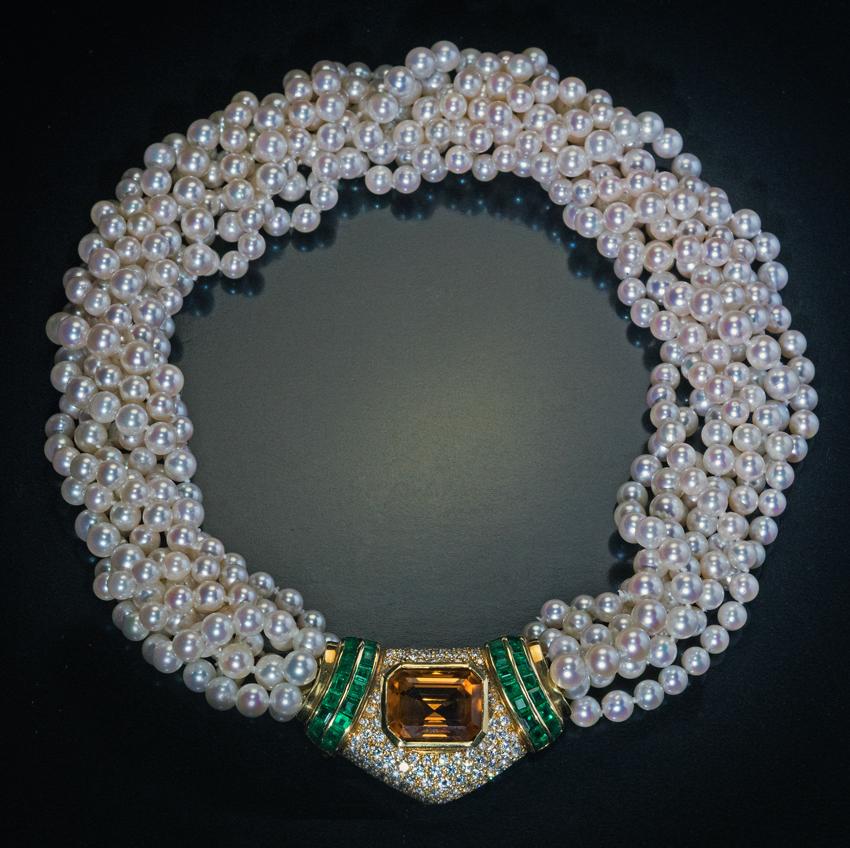 Questa collana vintage di perle coltivate della metà del XX secolo a sette fili è arricchita da una grande chiusura gioiello in oro 18 carati. La chiusura è centrata da un citrino taglio smeraldo circondato da diamanti e affiancato da smeraldi a