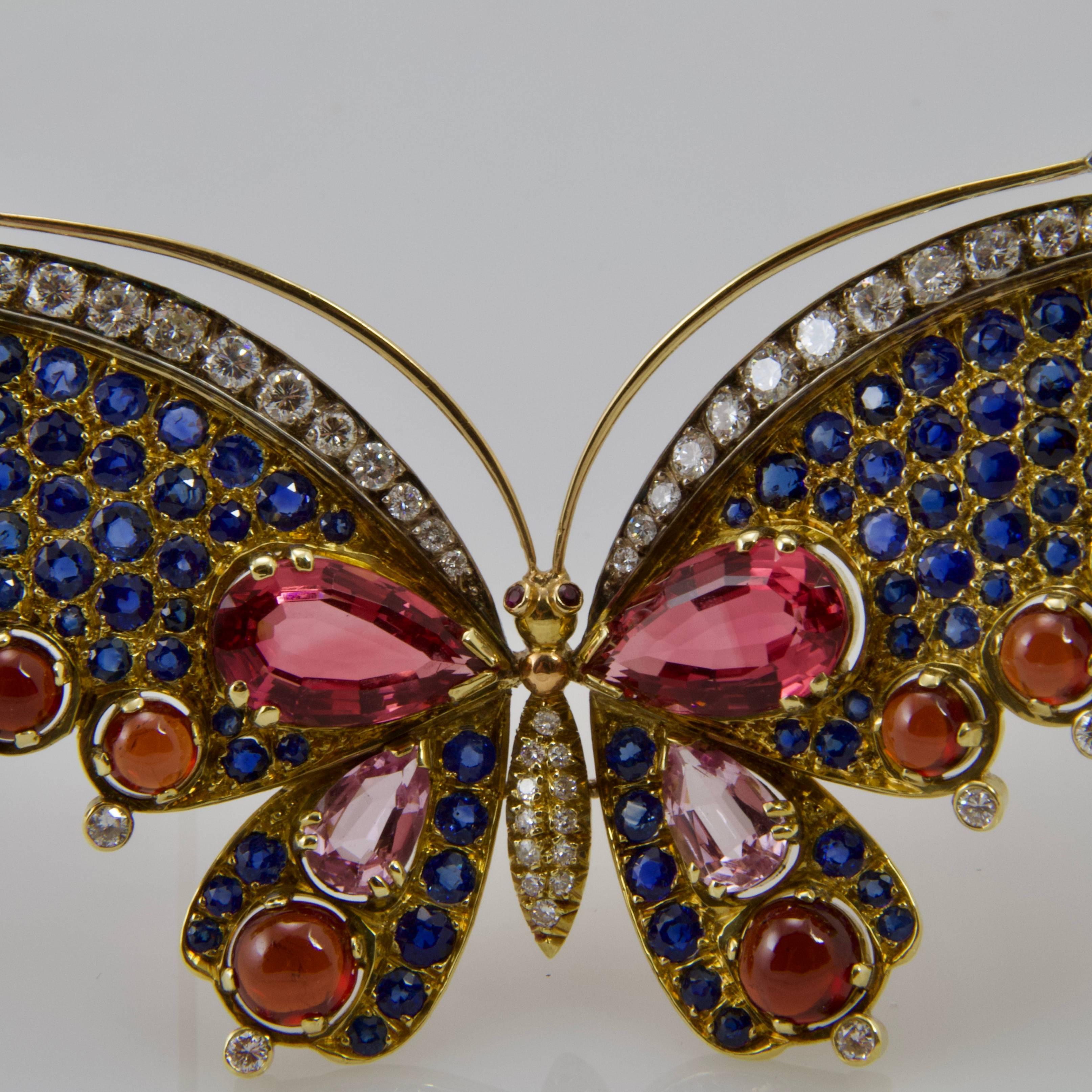 Large 18kt yellow gold butterfly brooch announcing the spring, set in a fresh harmony with rounds diamonds, rounds blue sapphires, pear-shape tourmaline strong pink and light pink and red garnet cabochon. Nice stones very colored.  
Made in Paris