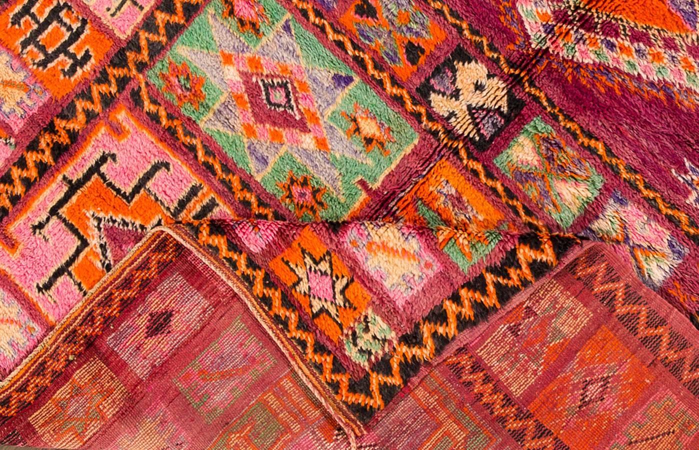 Vintage 1960s Moroccan carpet. This piece has an light purple field with a multicolored, geometric patchwork-style design. Measures: 5.10 x 9.03.