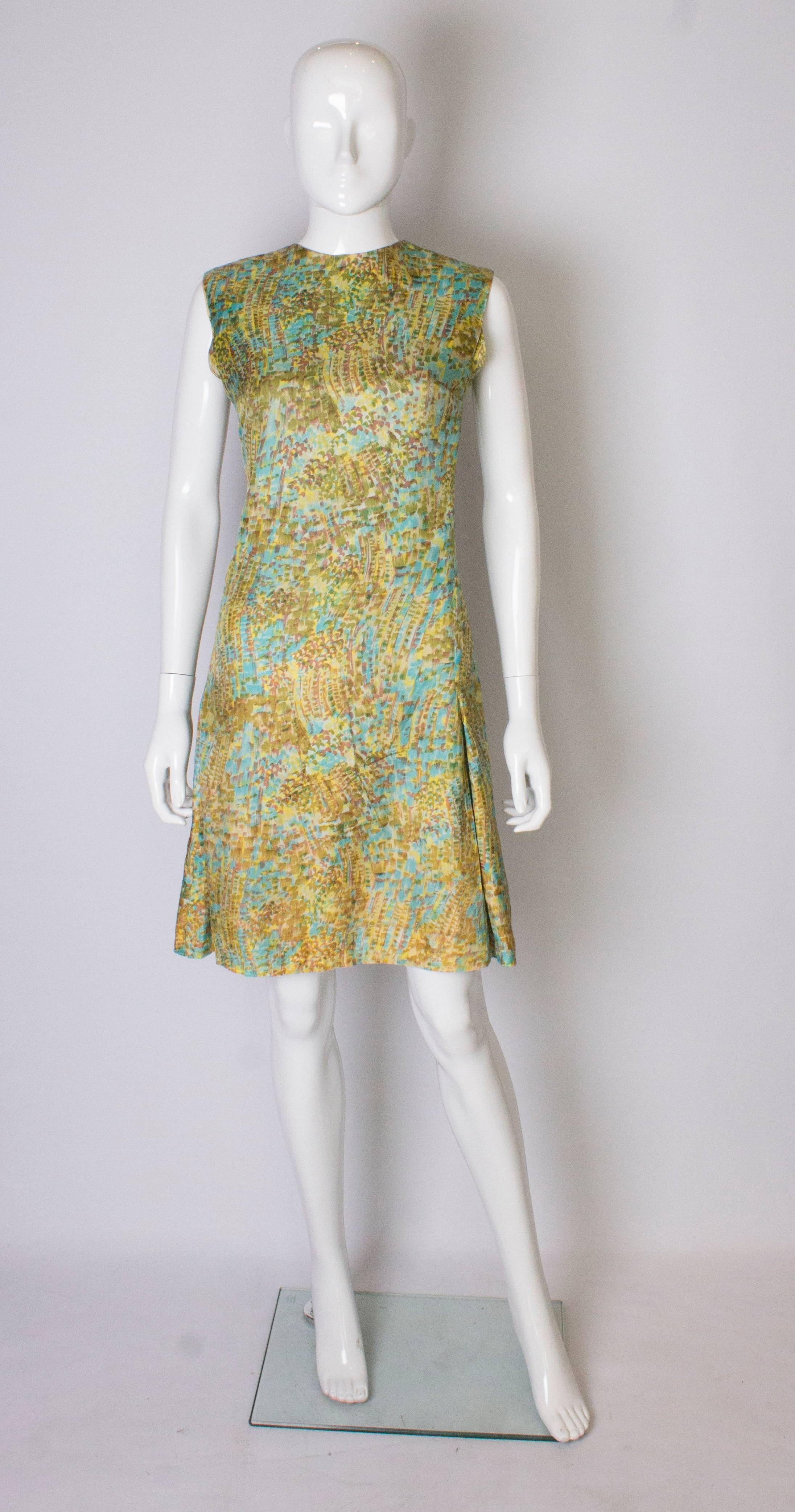 A  chic dress for Summer, a multicolour shift dress in blue, yellow and green. The dress is fully lined with a central back zip , and two pleats on the front and back.