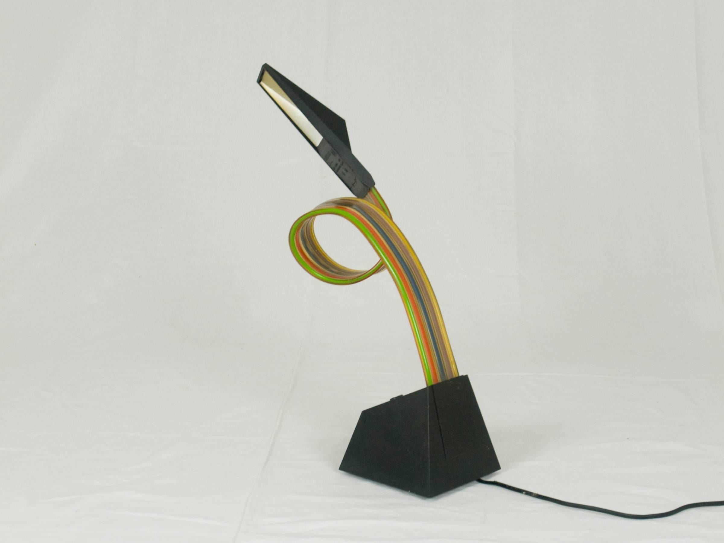 Table lamp with flexible multicolored extruded pvc stem with electrical cabling rising from a polycarbonate weighted base. It remains in a good vintage condition: just two small breakages close to the light bulb as showed in picture.