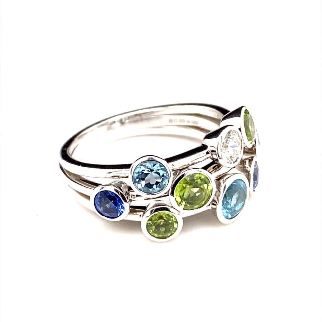 A vintage multigem and diamond set ring in 18 karat white gold.

This striking dress ring is set throughout with round brilliant cut diamonds, peridots, sapphires and aquamarines.

Each individual stone is set within a fine polished bezel setting of