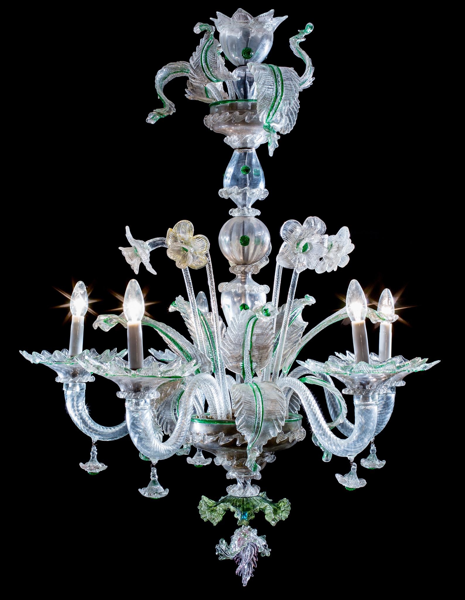 This lamp is a fine example of the unmistakable Murano style, which mixes the classic chandelier structure of a central axis made up of stacked hand-blown balusters and spindles, with a variety of more fluid, dynamic and sculptural floral and