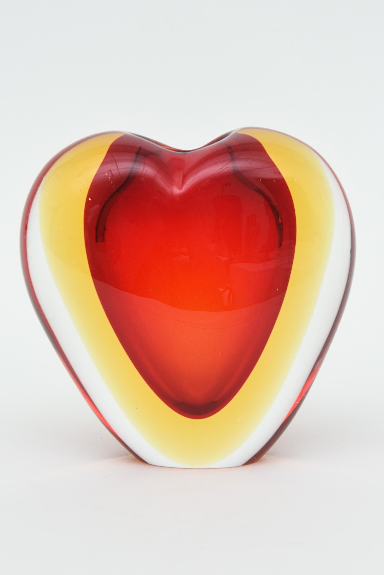 This vintage beautiful Italian Murano glass heart vase or object sculpture is by Antonio da Ros for Cenedese and from the 70's. It is layered sommerso glass in red, yellow then to clear. The shape is a heart and only a few small flowers will fit.
