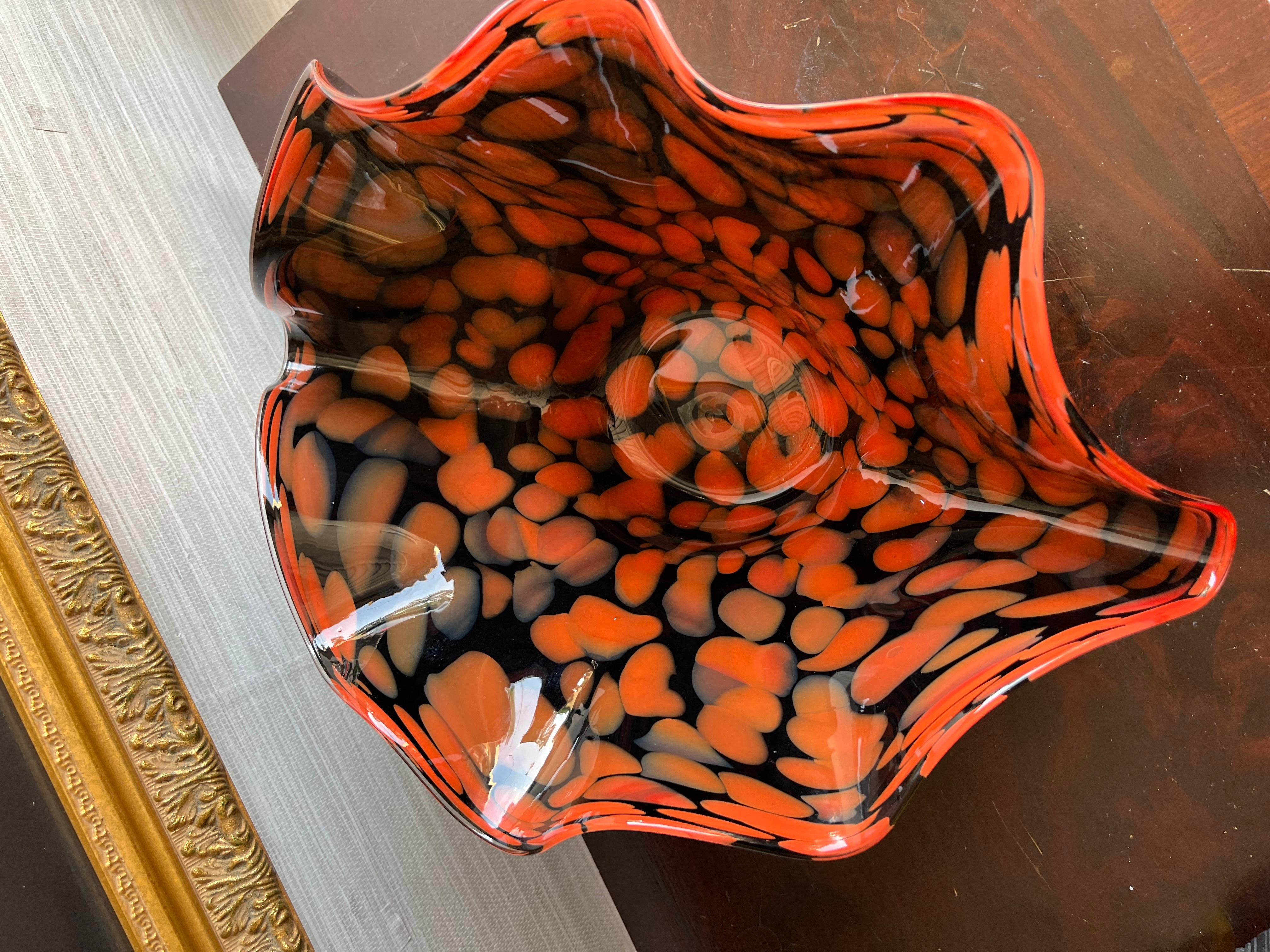 Ce vase décoratif en verre d'art de 18 pouces de large est un véritable témoignage de l'habileté et de la créativité de l'art du verre soufflé à la bouche. Fabriqué à partir de verre noir coulé, il forme gracieusement une forme unique de coquille de