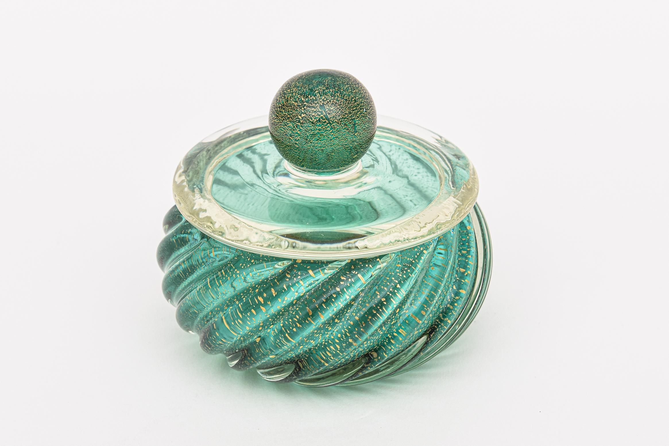 This luscious small vintage murano round glass box with a gold infused ball lid is by Barovier &Toso. It is from the 50's. The diagonal ribbed glass bowl are colors of sea green blue and emerald green with gold aventurine. The round ball glass top